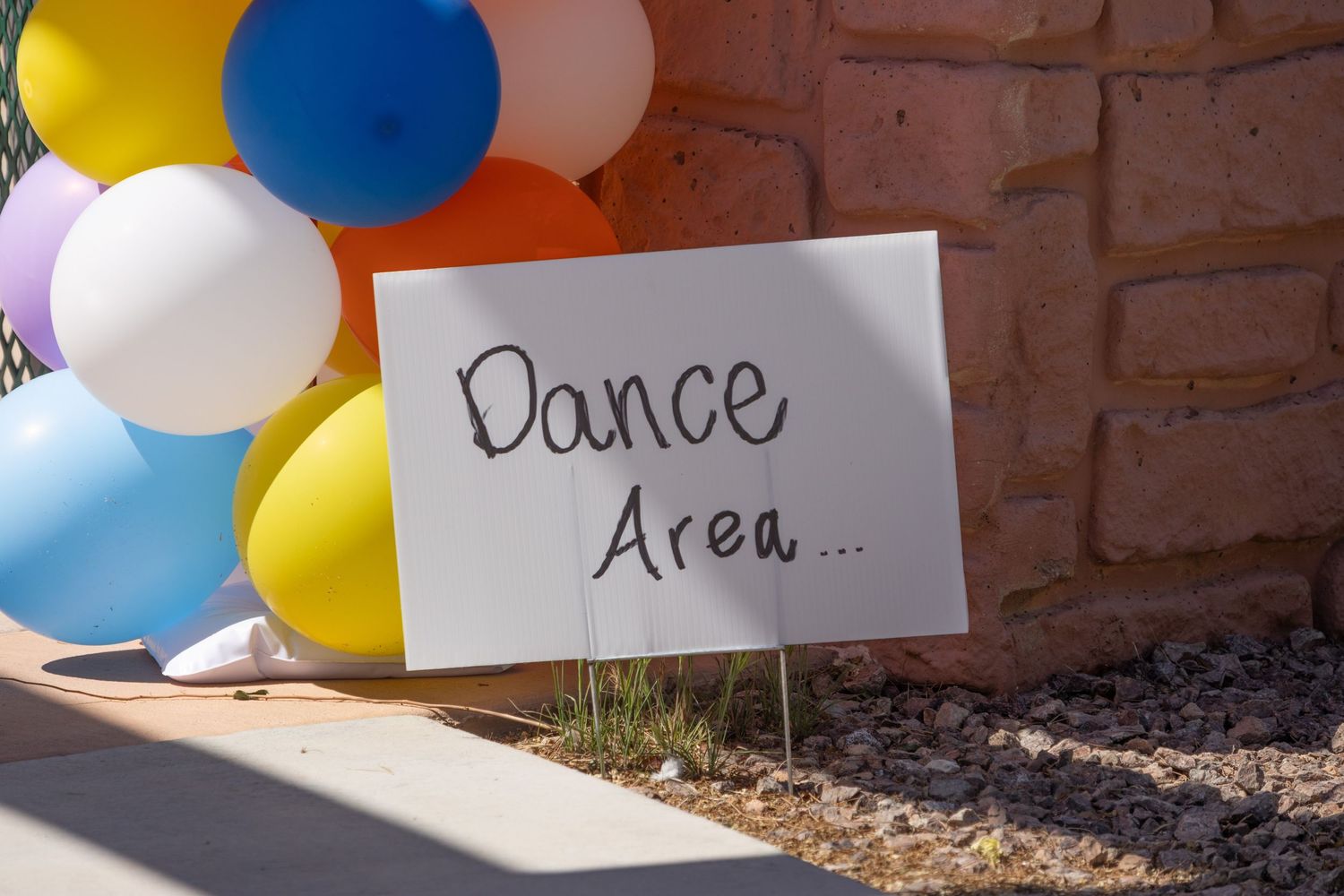 Colorful balloons and signage marking designated areas at outdoor event.