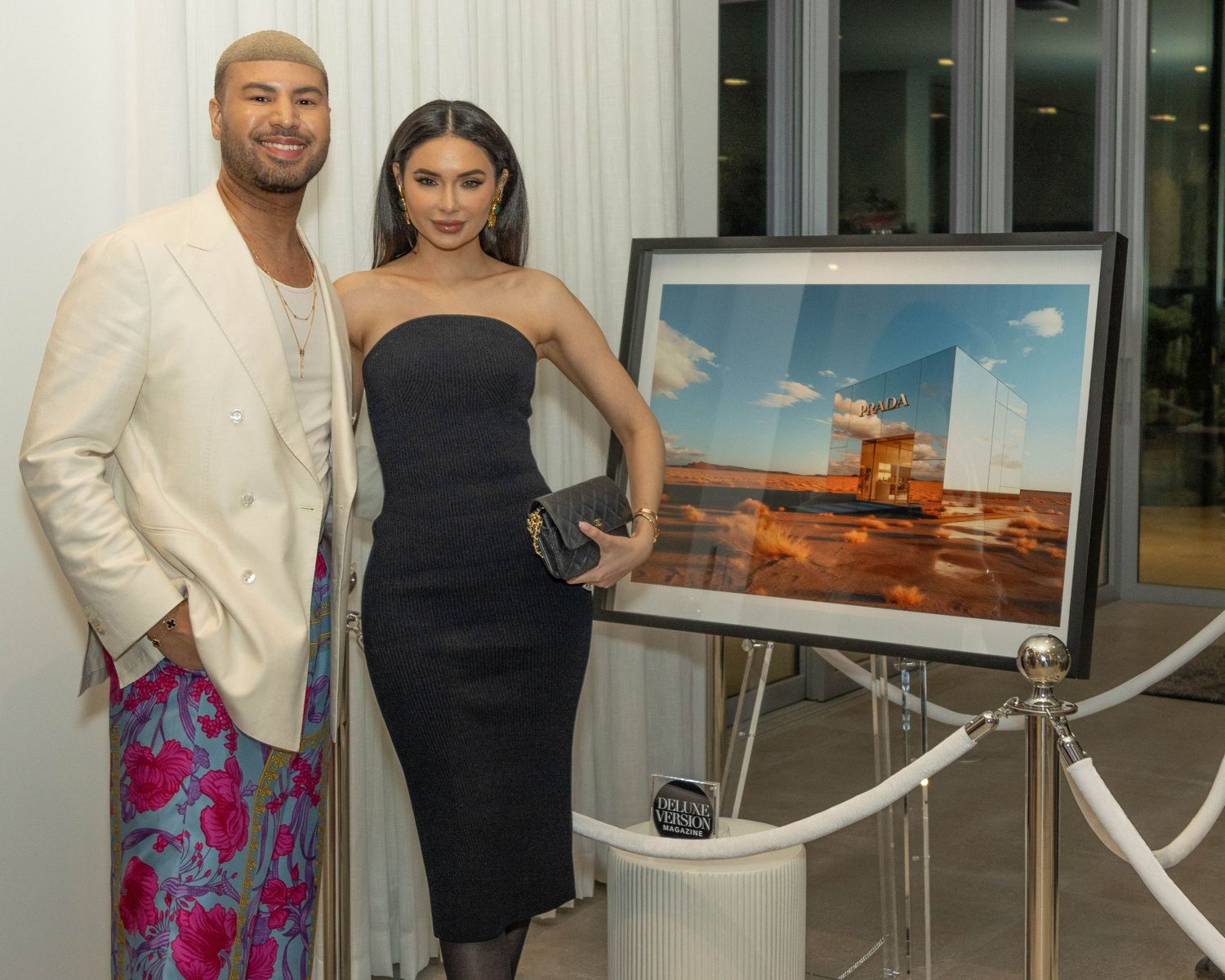 Guests mingle and pose at an elegant indoor social gathering with artwork displayed on the walls.