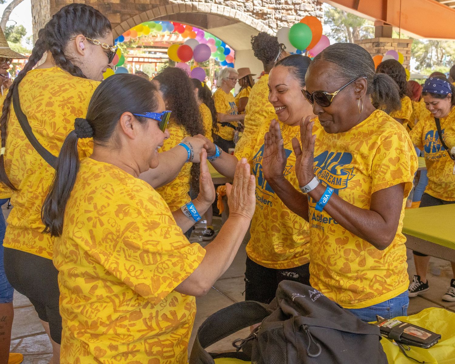 Group wearing matching yellow shirts participates in activities under a covered pavilion.