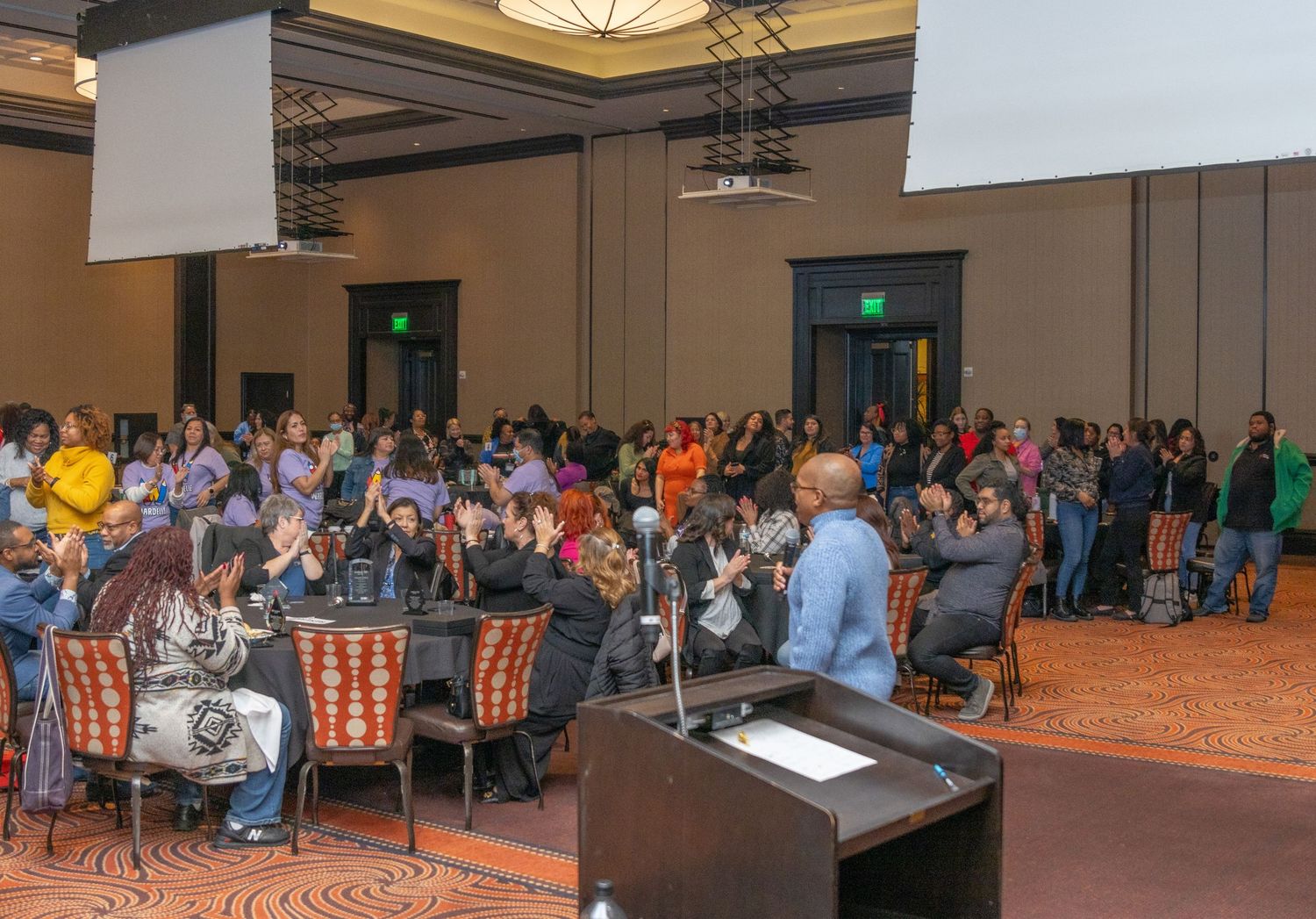 Panoramic view of a large conference hall with guests seated for a presentation.
