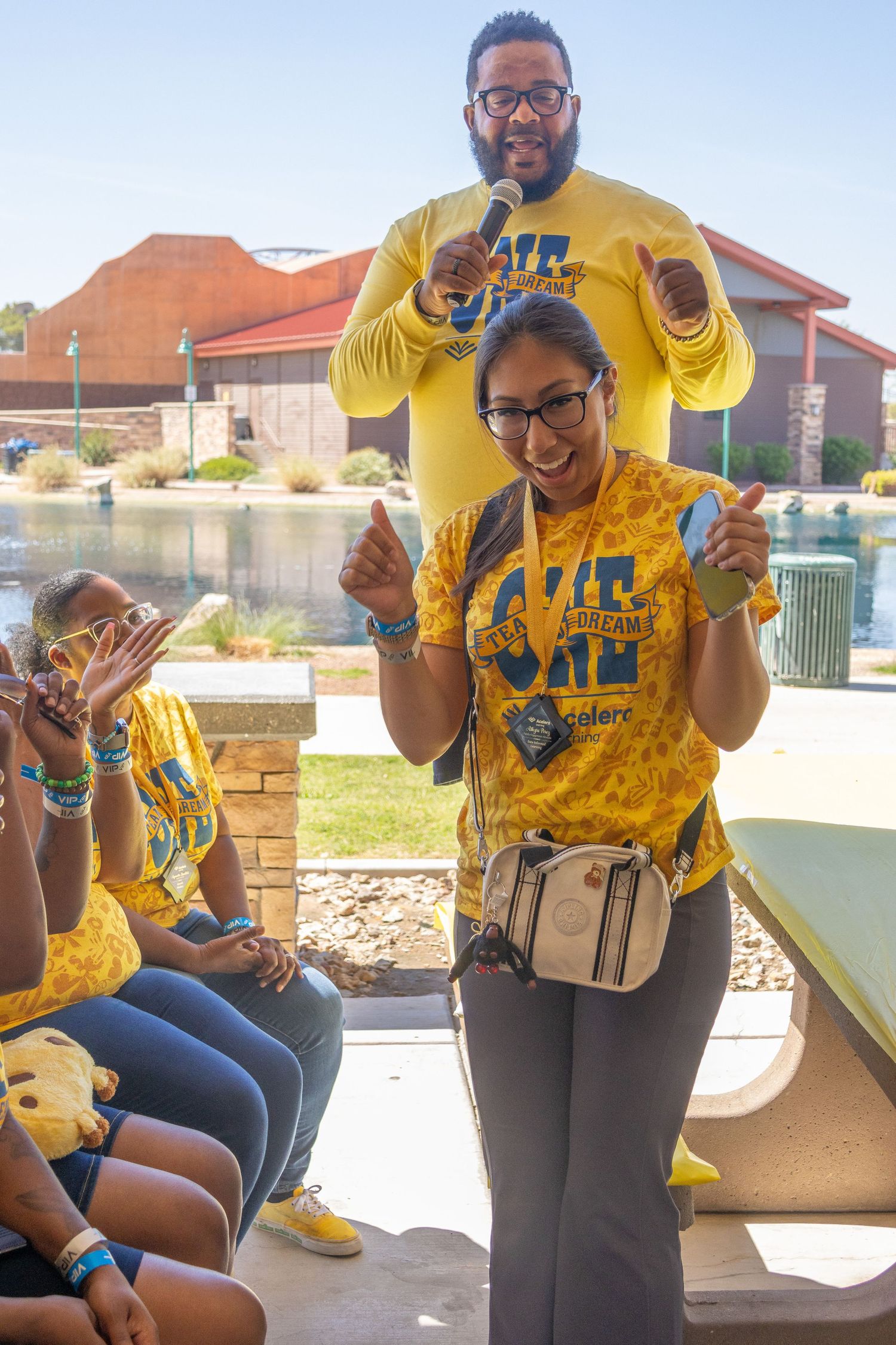 Group wearing bright yellow t-shirts gathering outdoors on a sunny patio.