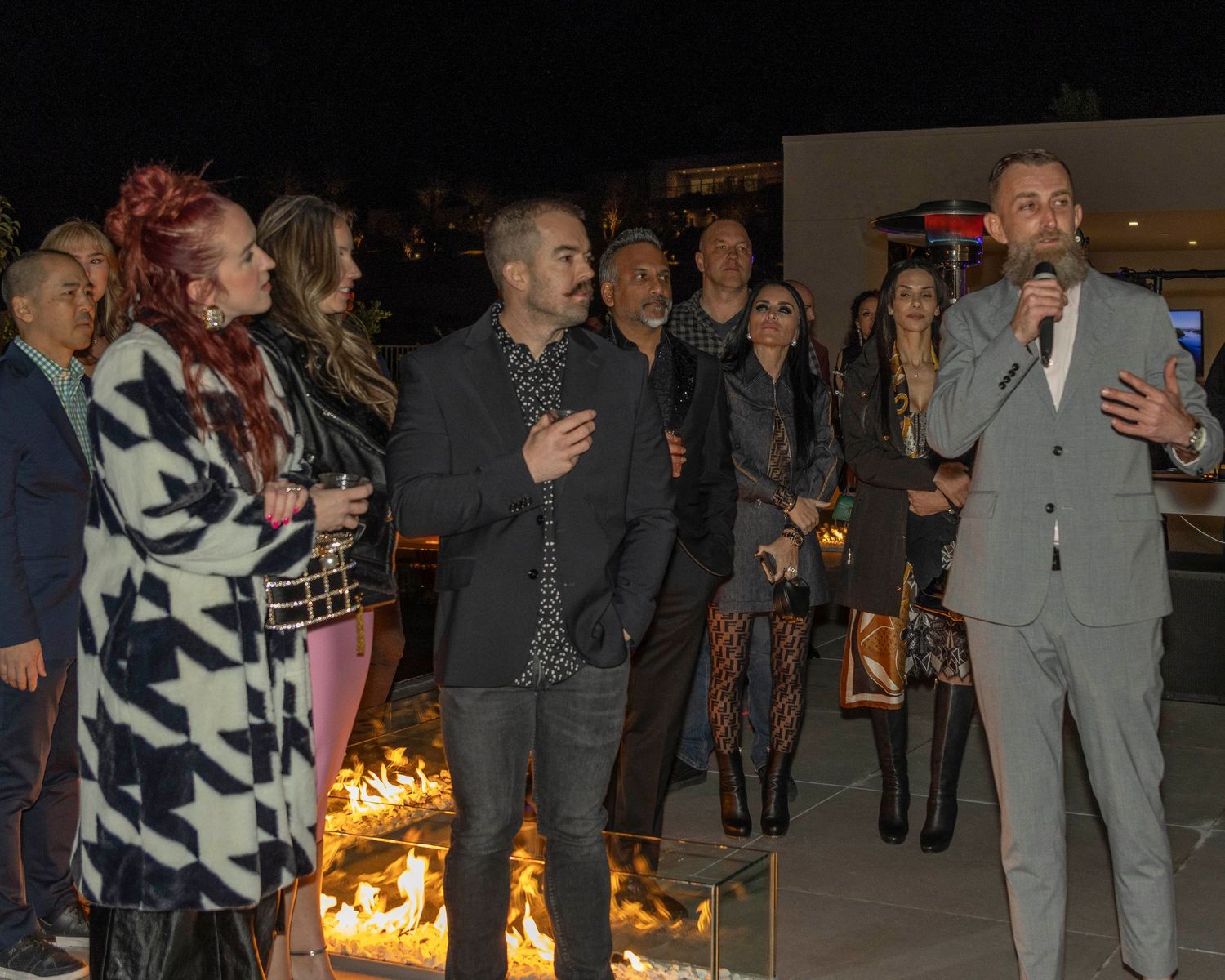 People gathered around an outdoor fire pit at night during social event.