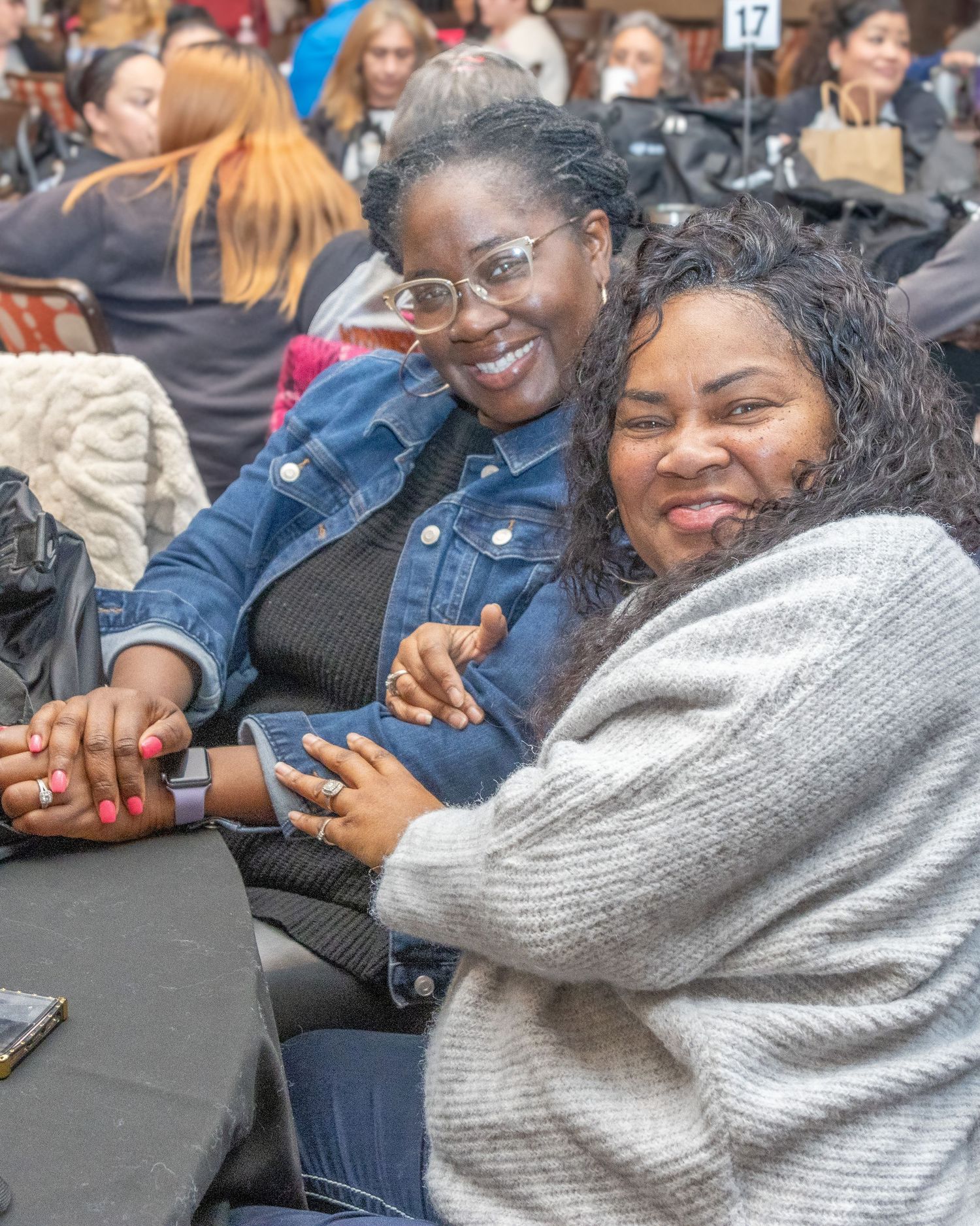 Students sitting together and laughing during indoor gathering with warm lighting.