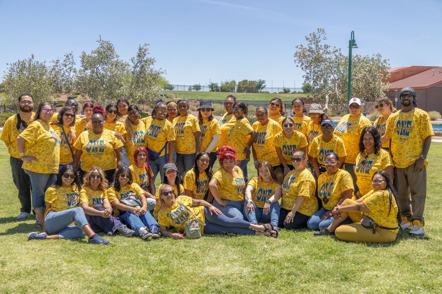 Team members in bright yellow uniforms arranged in a long line on sunny grass field.