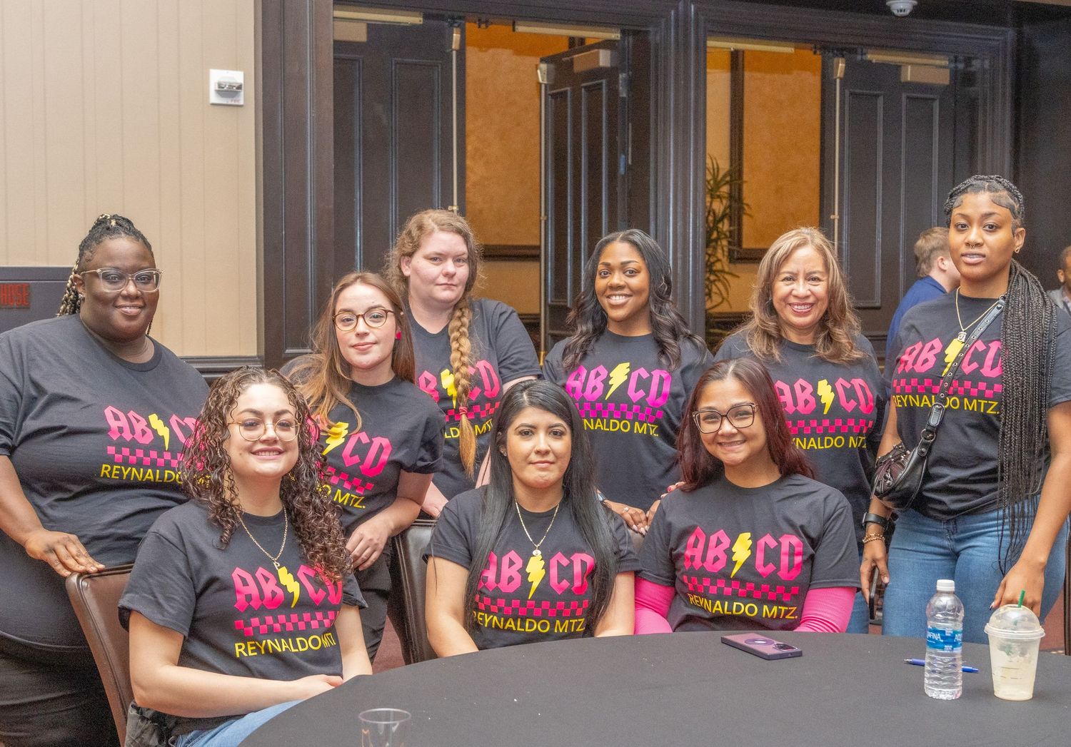 People wearing matching t-shirts pose together at a group event.