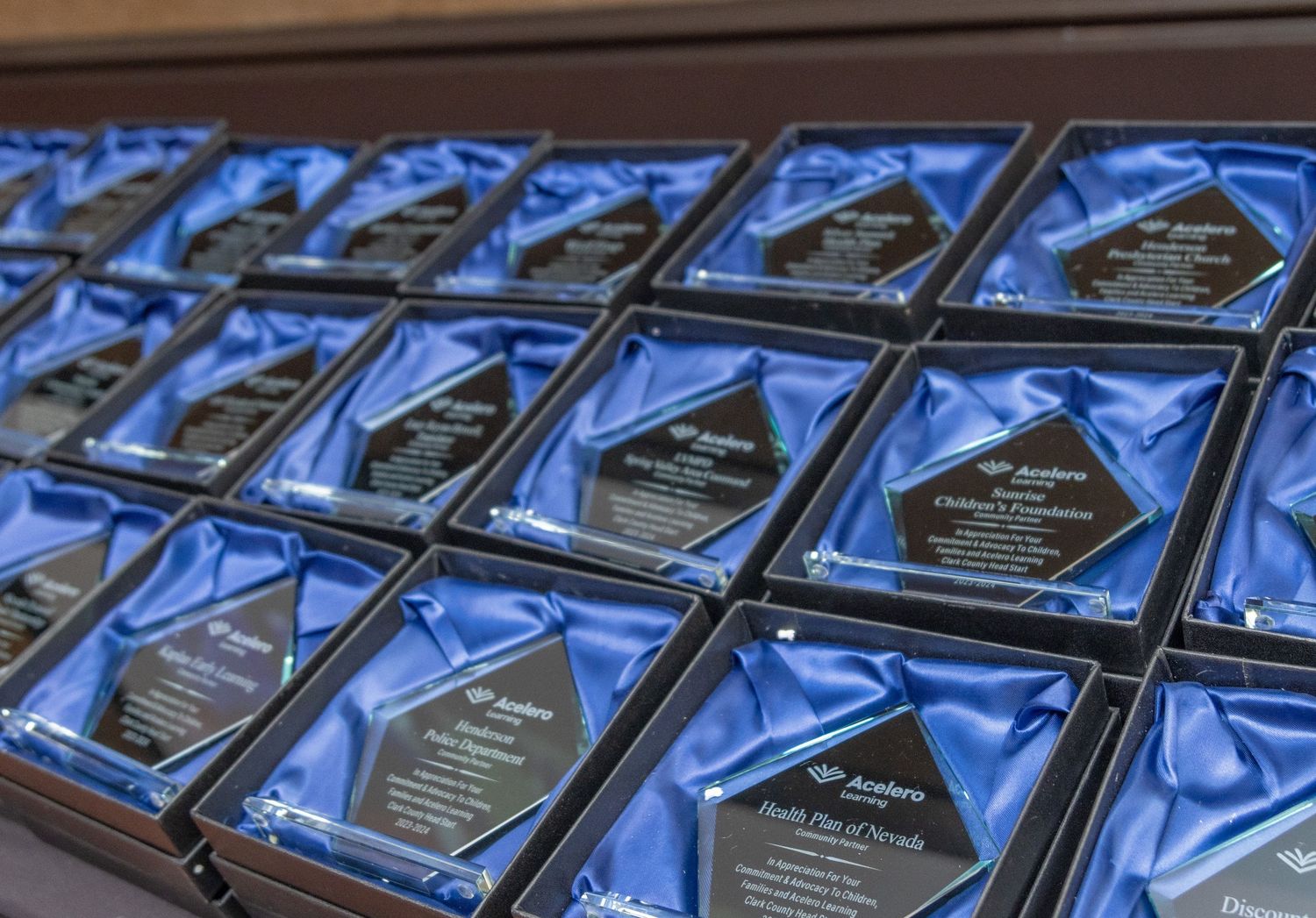 Display of diamond-shaped crystal awards arranged on blue satin background.