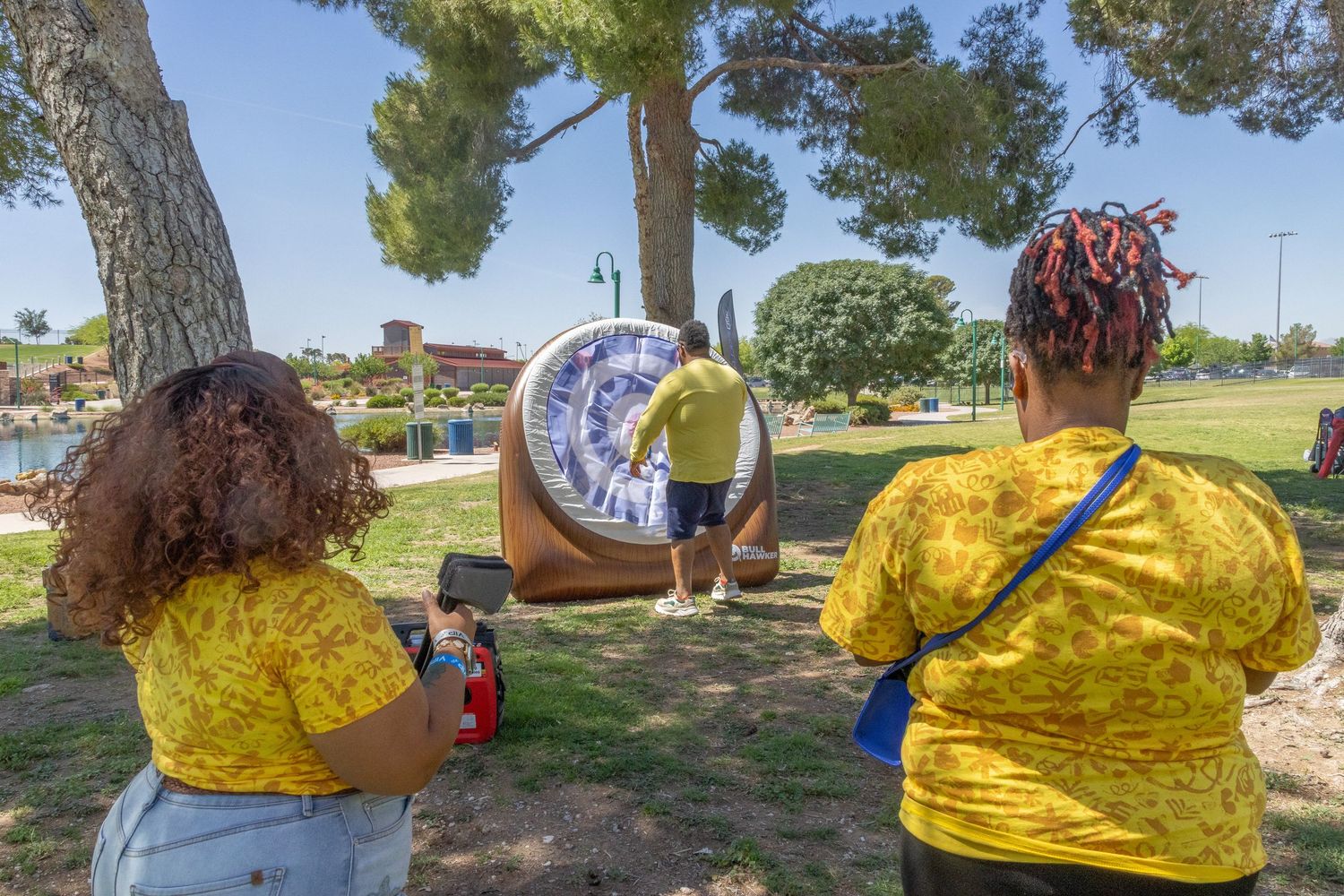 Team members in yellow shirts engaged in outdoor activities at a sunny park.