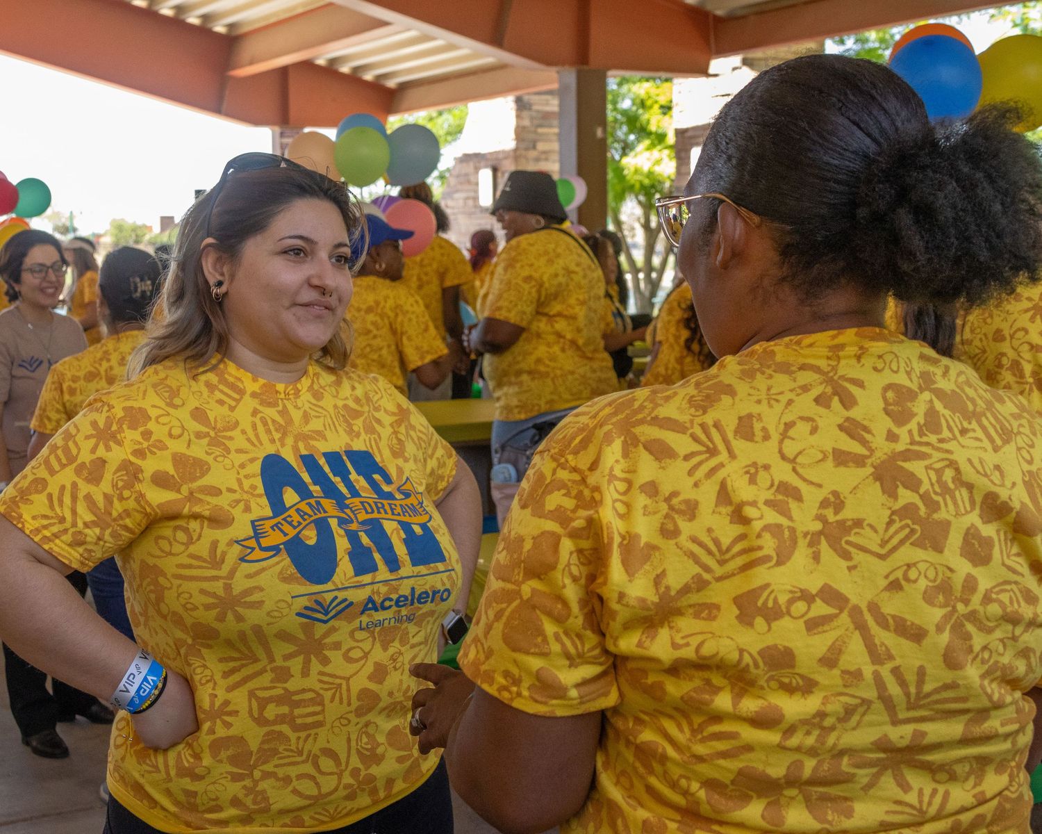 People in yellow patterned shirts mingling at outdoor community celebration.