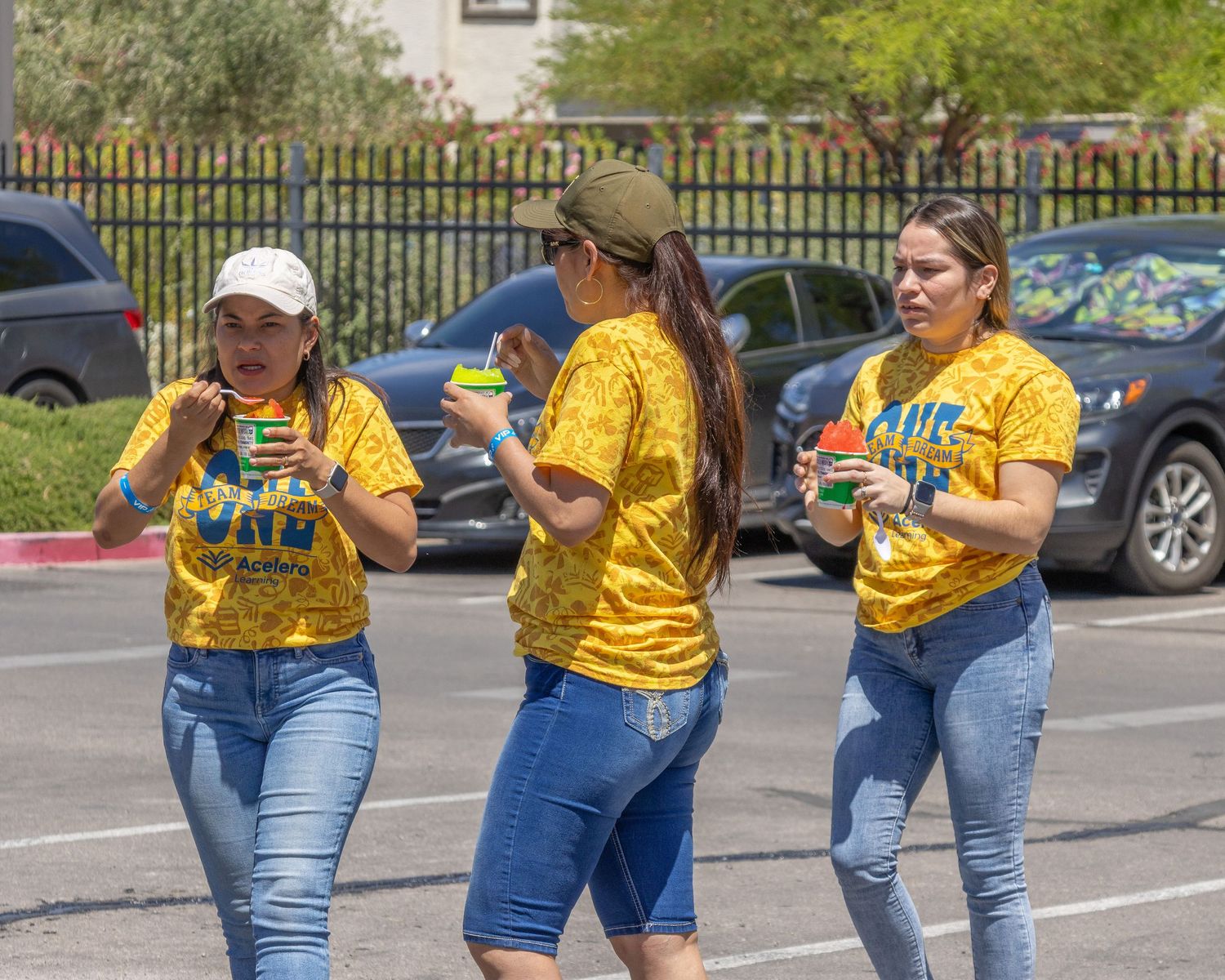 Volunteers in bright yellow t-shirts and blue denim walk together through a parking area during an outdoor event.
