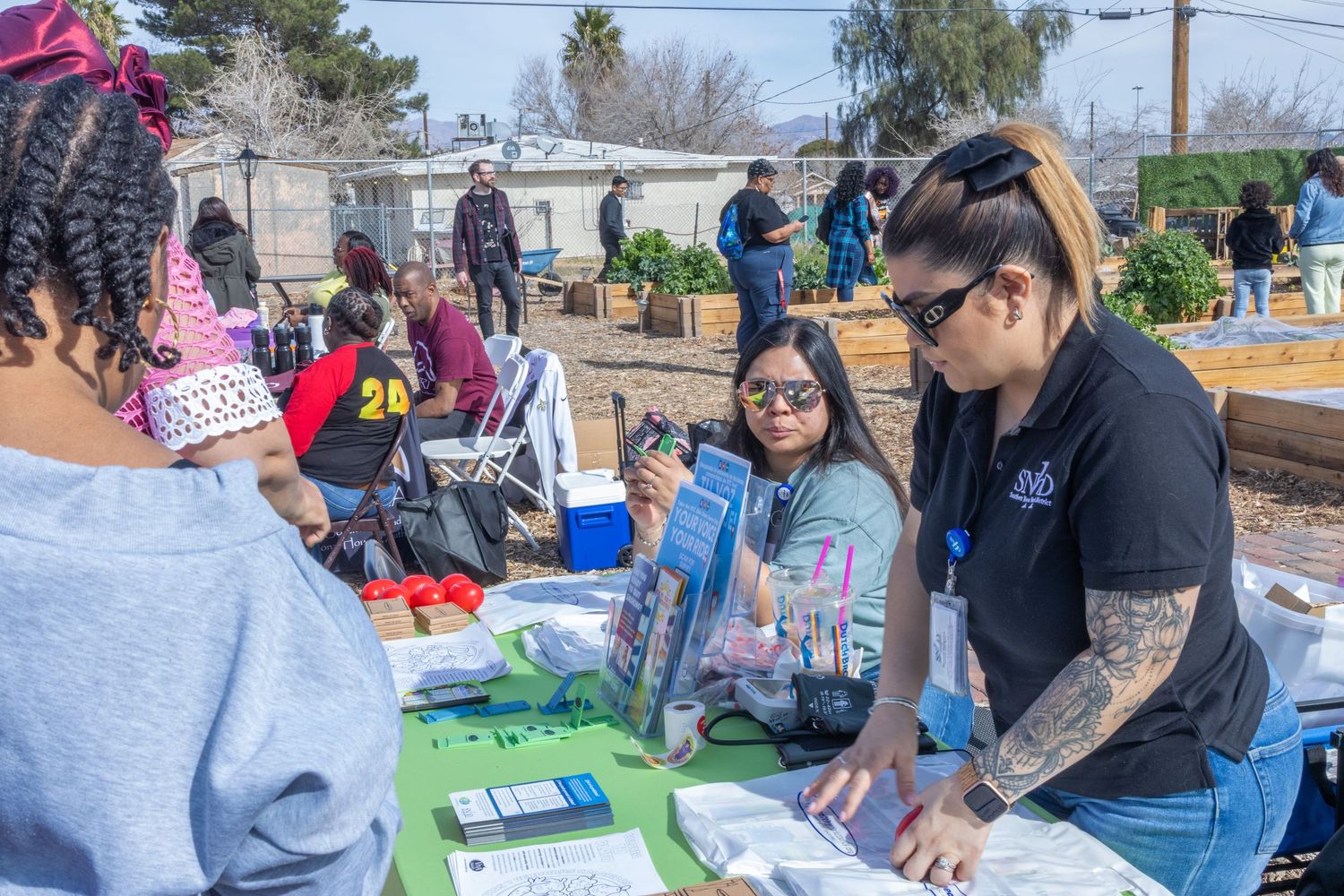 A hands-on workshop session shows participants gathered around tables working on art projects in an outdoor setting.