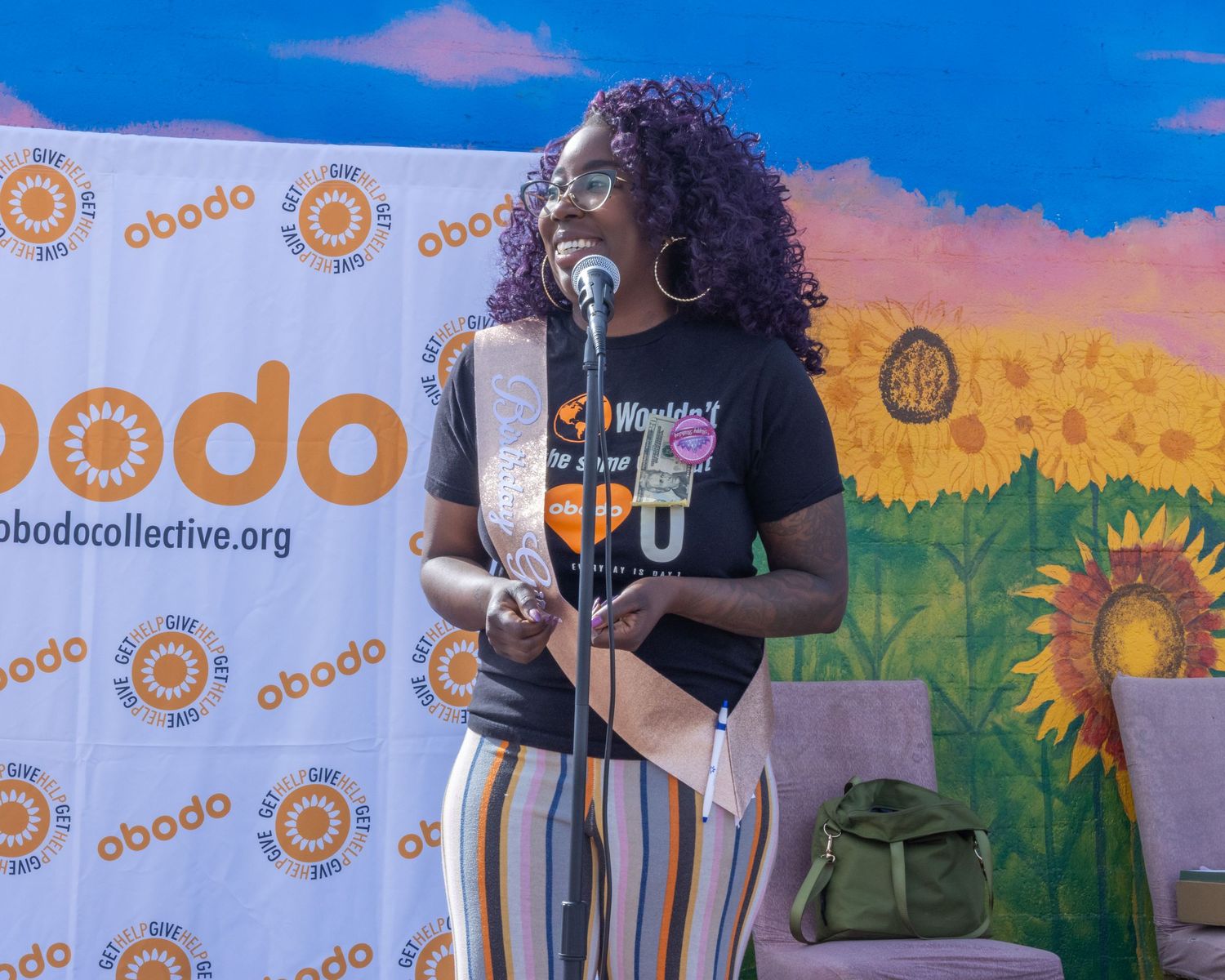 Musicians perform on stage in front of a colorful mural backdrop with sunflower logo designs.