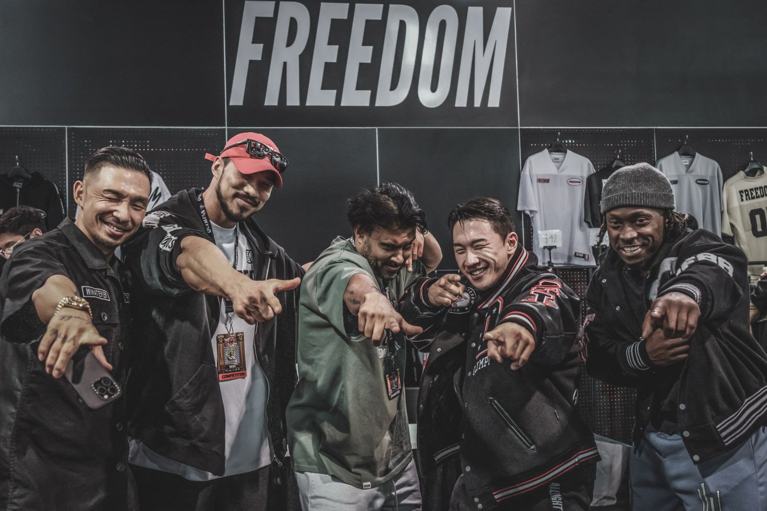A group of athletes performing CrossFit exercises together in a dark gym with the word 'Freedom' visible on the wall.