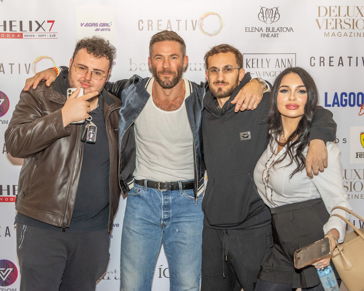 Group photo session at entertainment industry event with promotional backdrop.