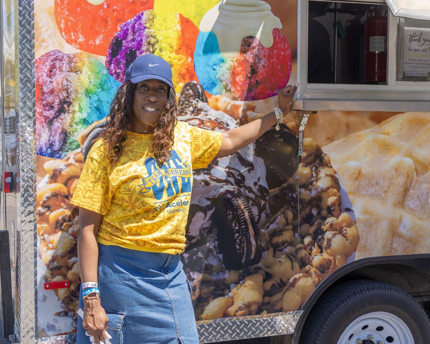 Colorful food truck with vibrant graffiti art and customers waiting in line on a sunny day.