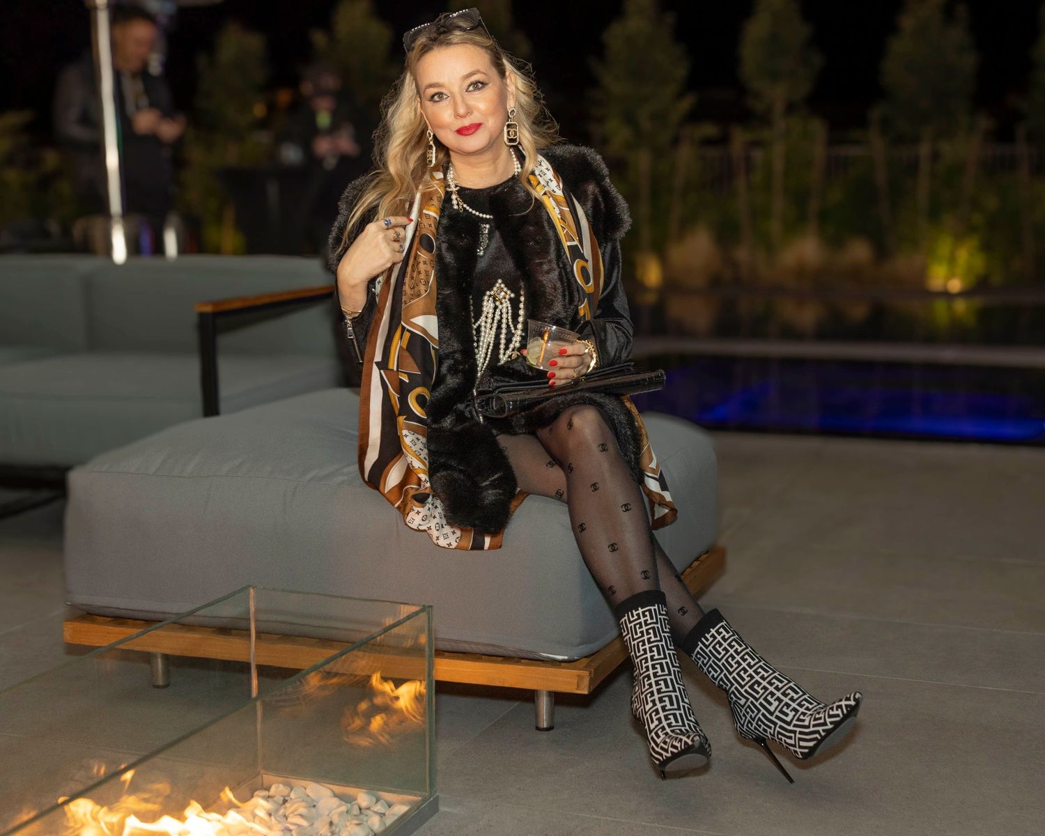 Stylish party scene with people gathered around an outdoor fire pit.