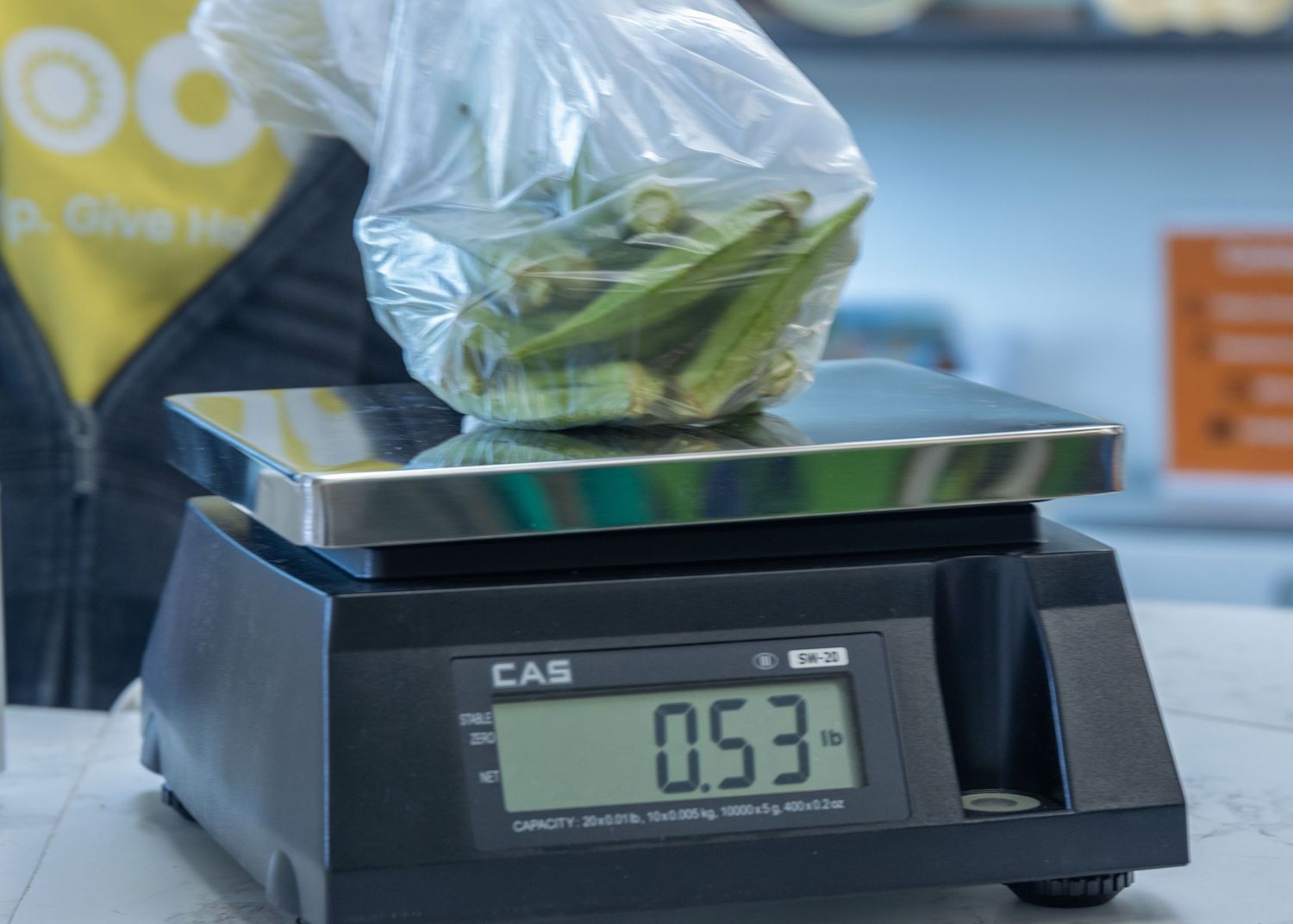 A digital CAS scale displays 0.53 while weighing fresh produce in a clear plastic bag.