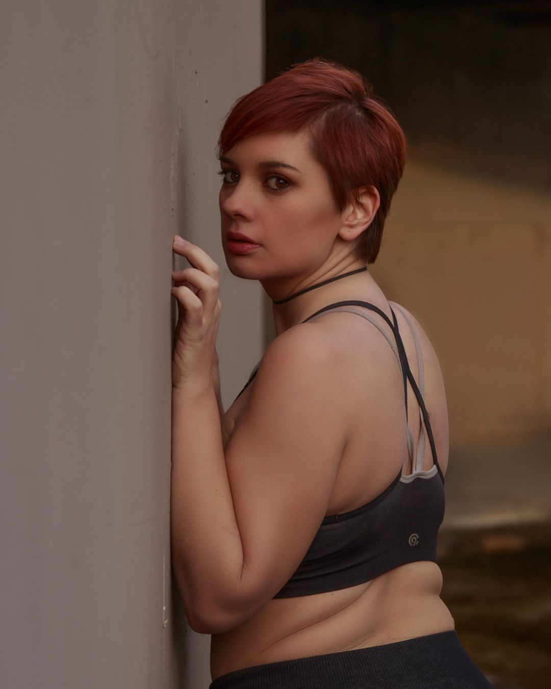Artistic boudoir photography featuring moody lighting and intimate poses against a wall.
