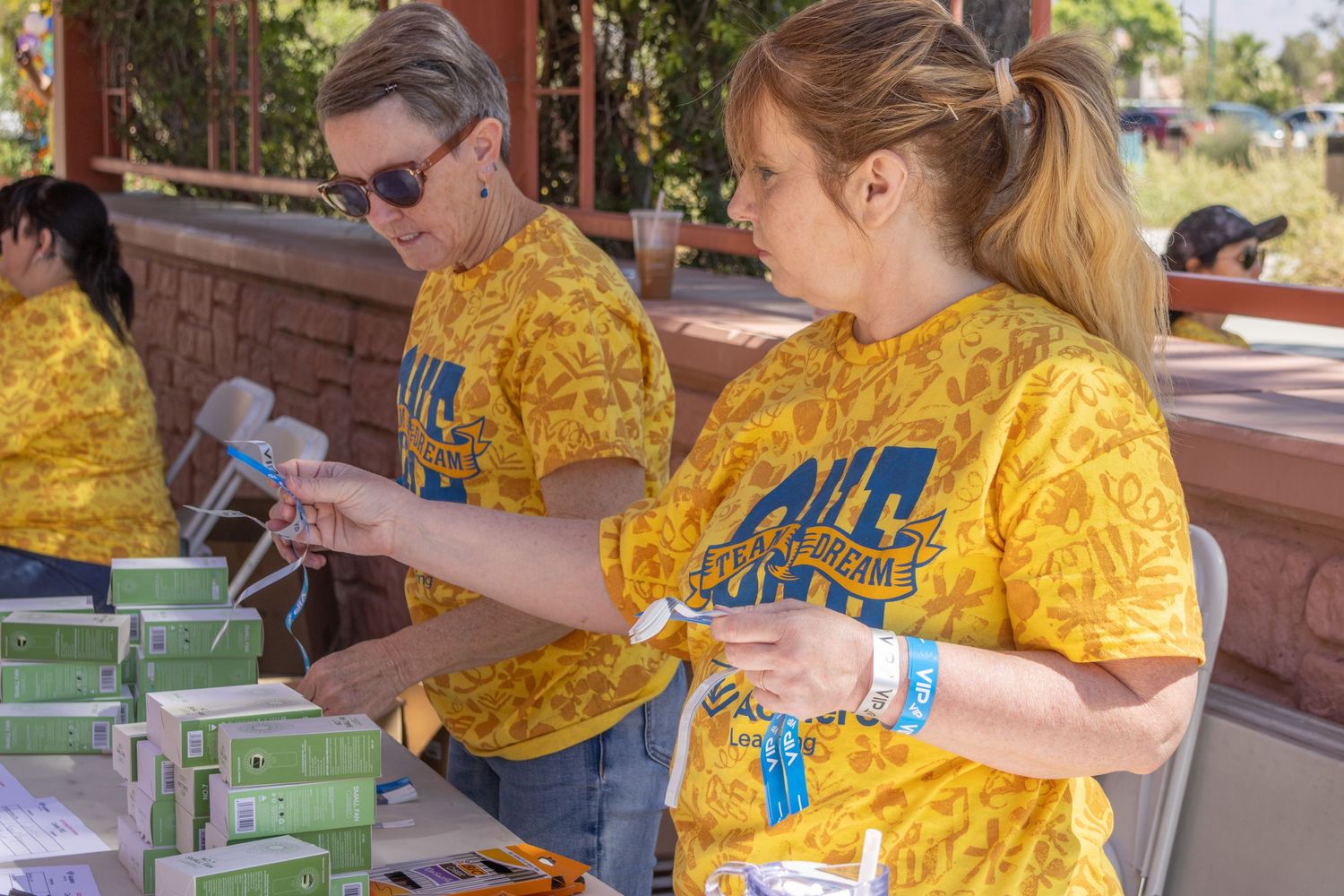 Volunteers in bright yellow shirts staffing activity stations at an outdoor community event.