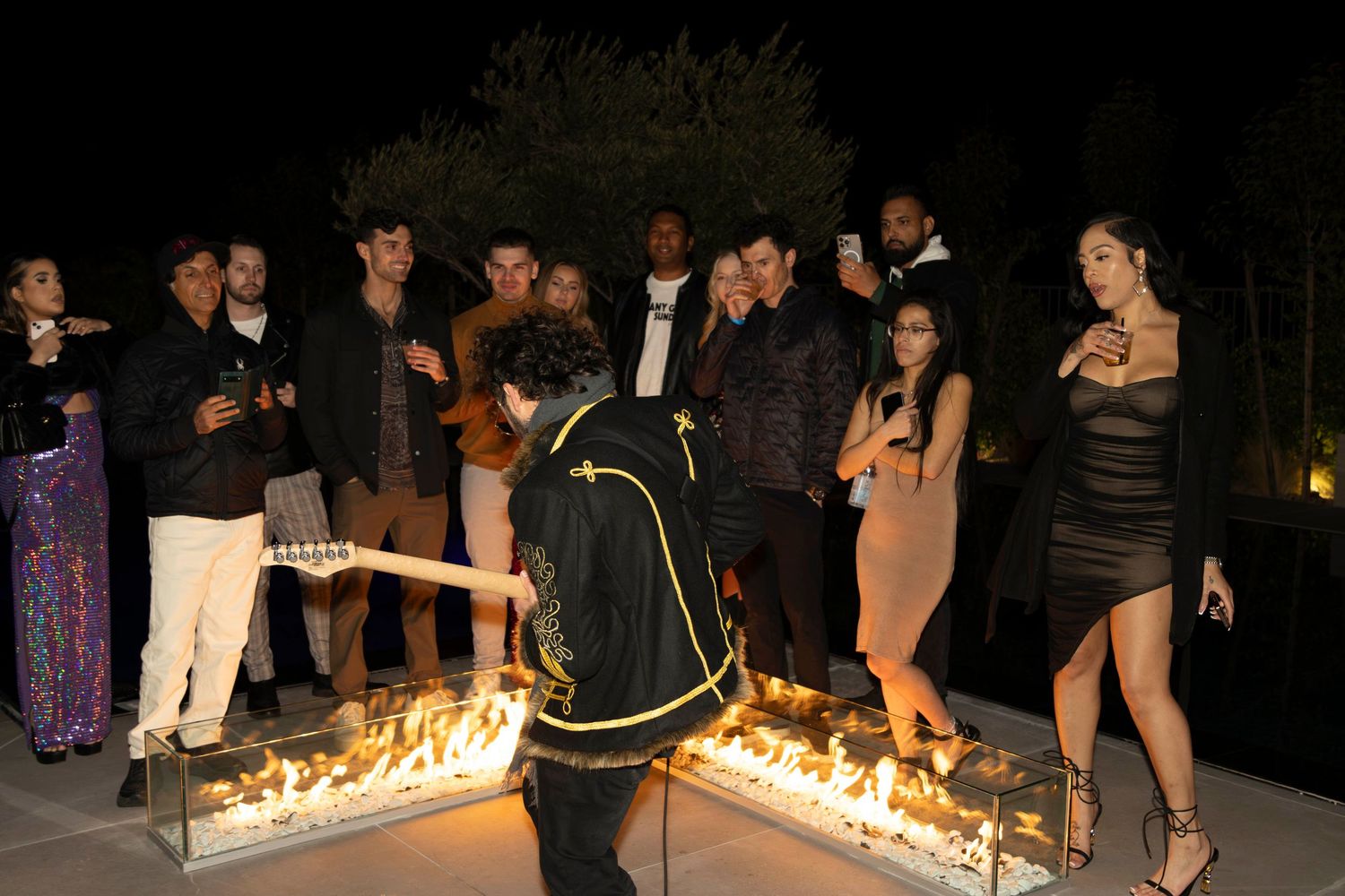 Outdoor event space with fire feature and crowd gathering in evening setting.