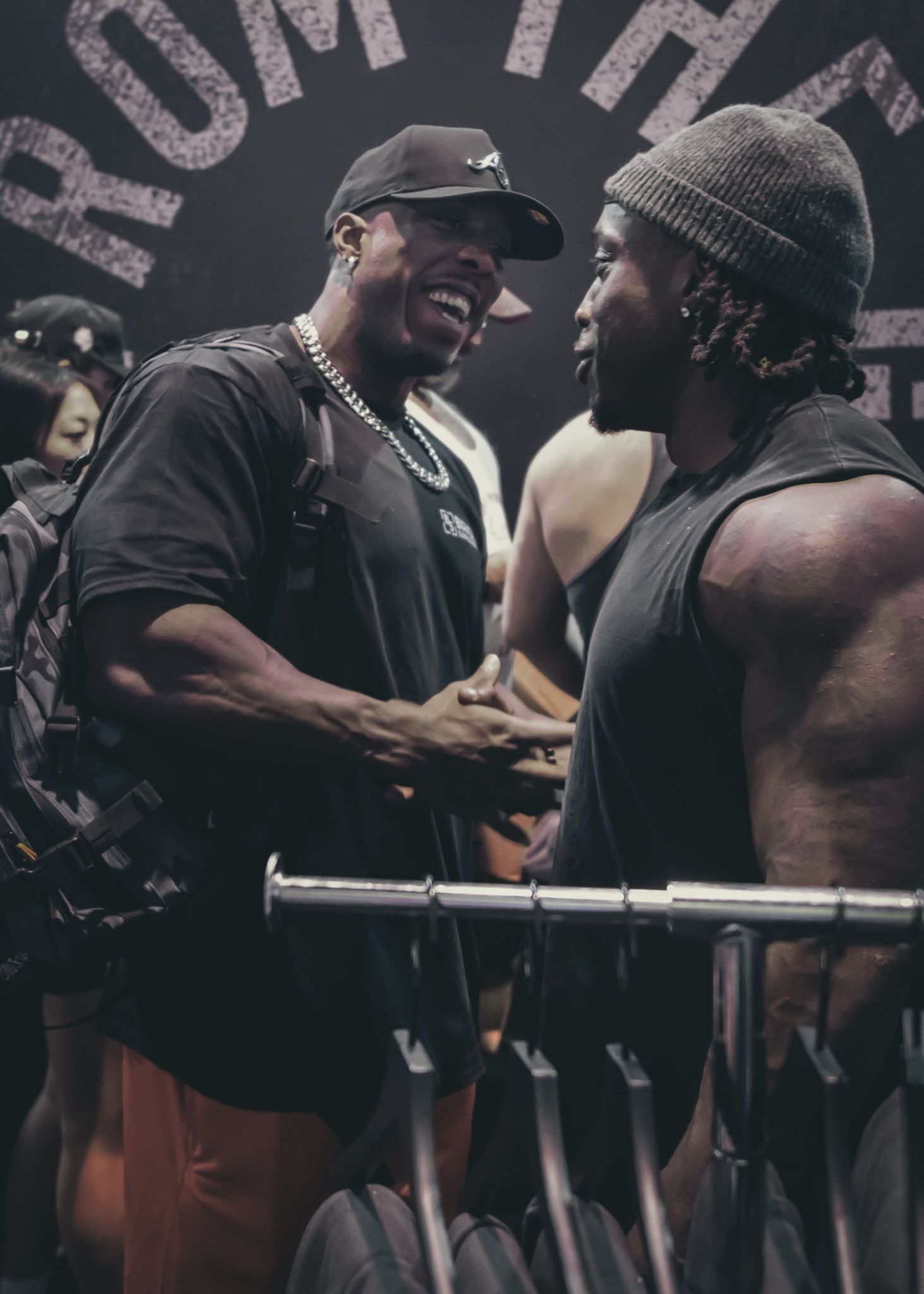 A group of people watching and participating in an intense arm wrestling match at a tournament venue.