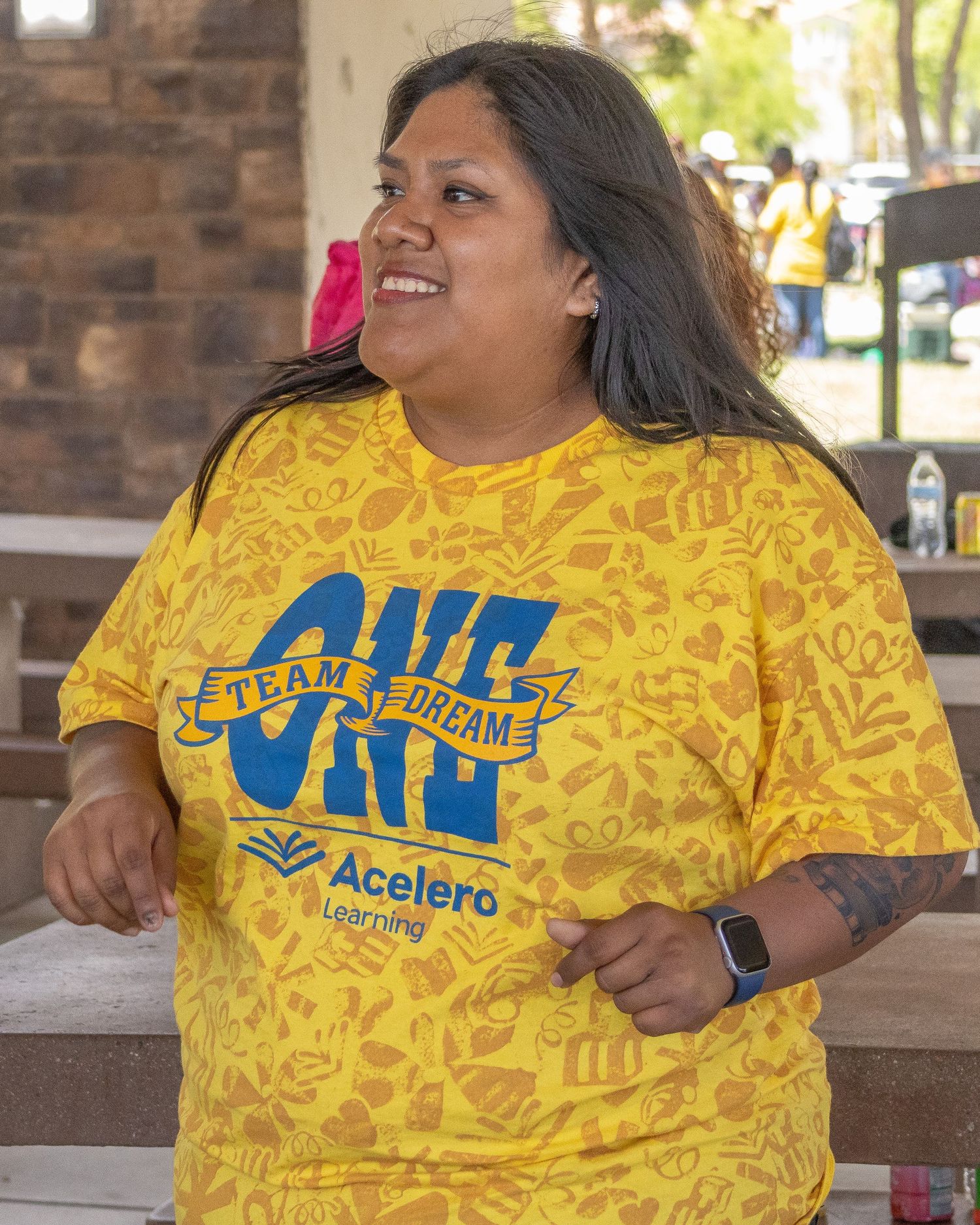 Person wearing yellow Accelero team shirt smiling during outdoor event.