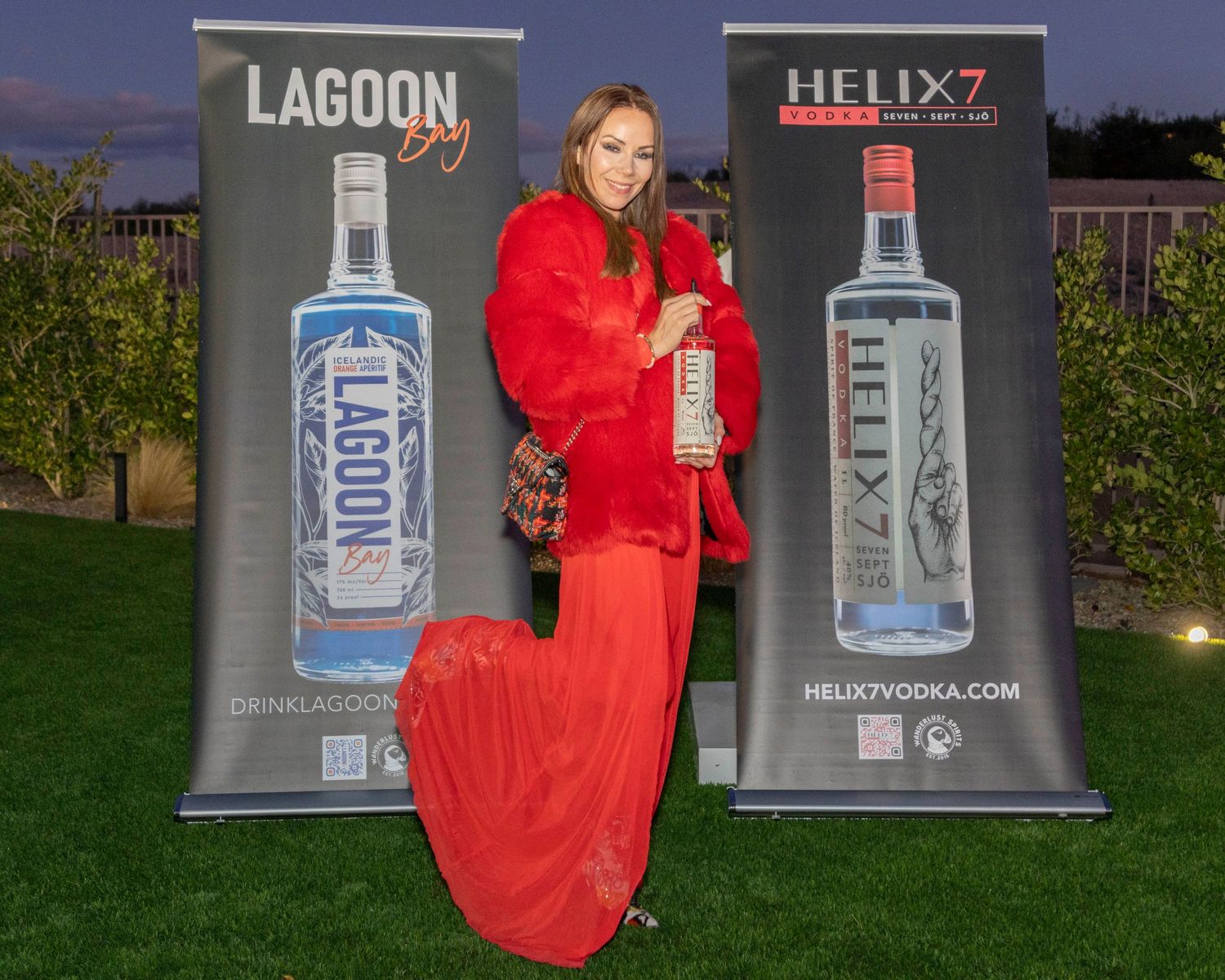 Outdoor nighttime promotional event setup with vodka bottle displays and red decor.