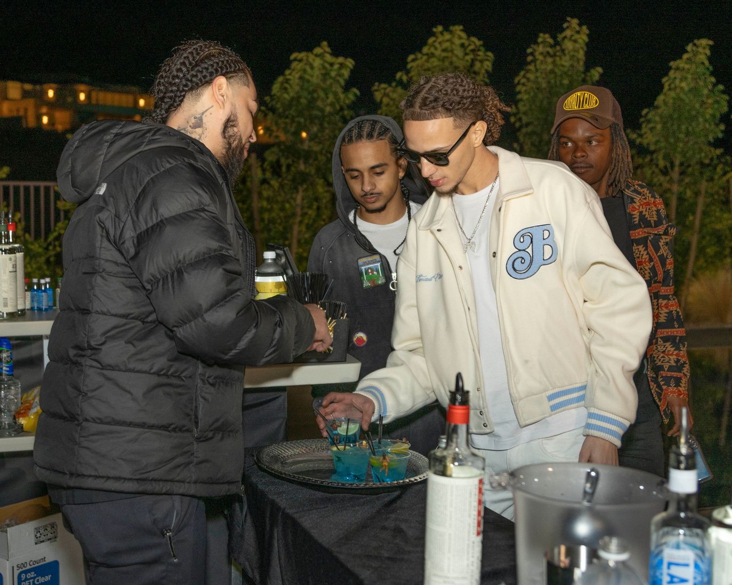 Outdoor nighttime event with people gathered around tables with refreshments. Only1lacrosse