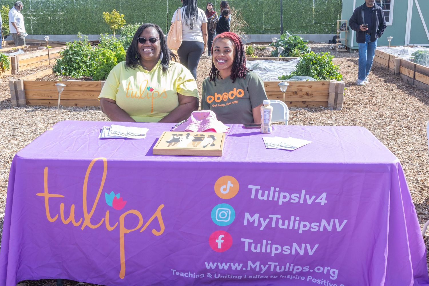 Purple branded table display for Tulips company with website and social media information shown on tablecloth.