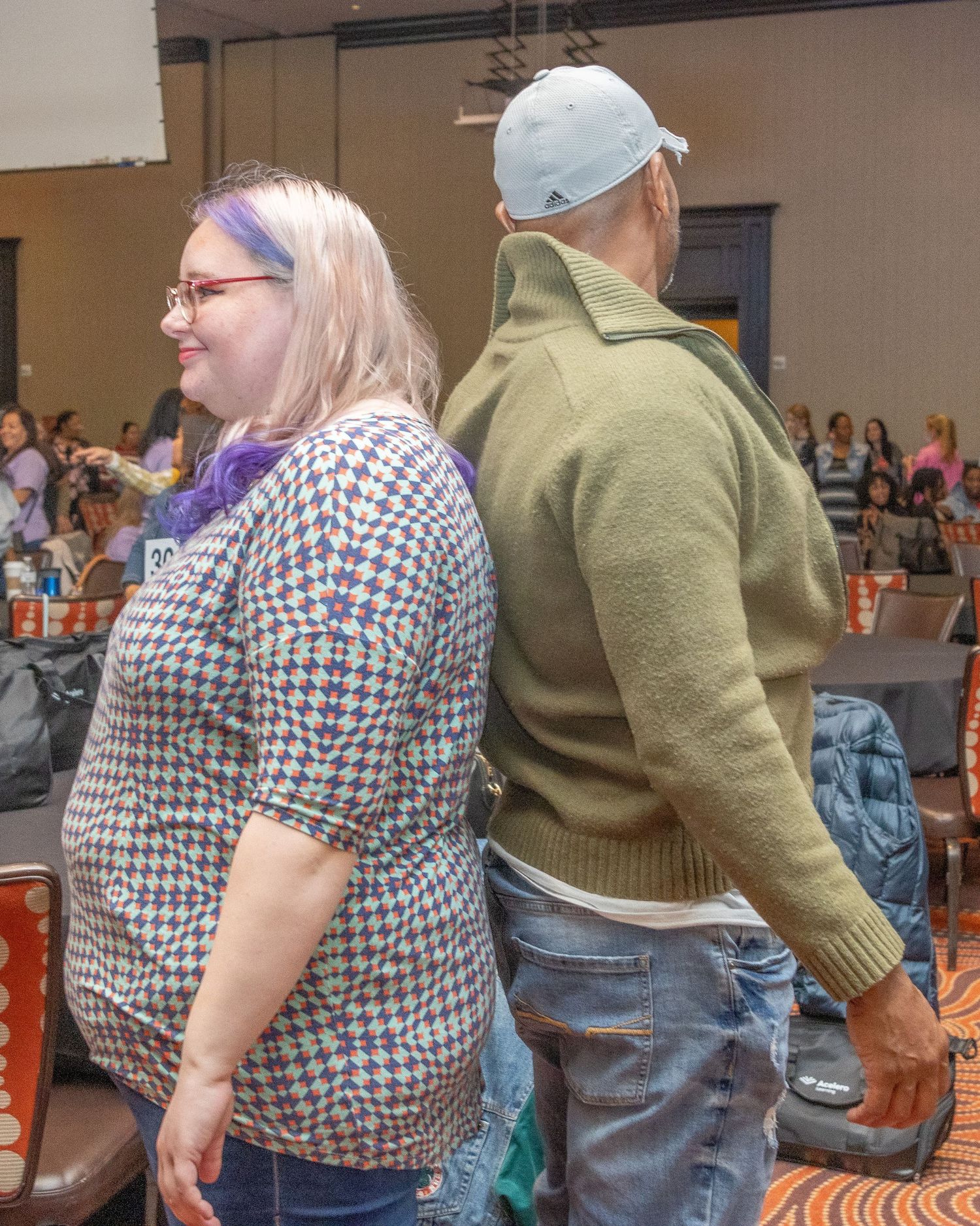 People dancing in a line at indoor social event wearing casual attire.