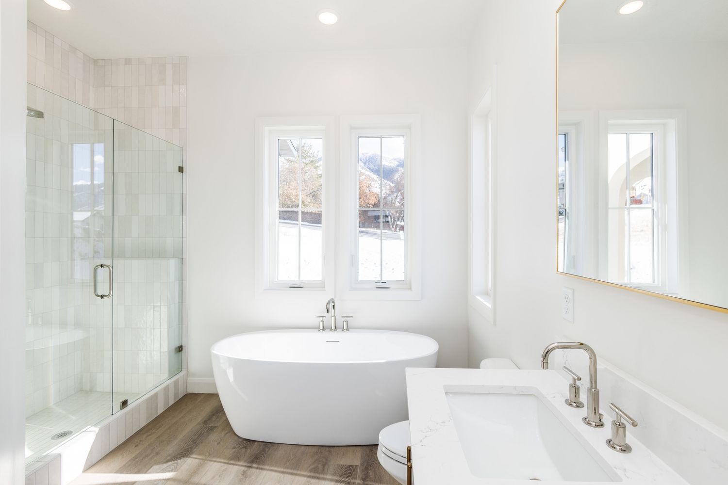 Bright white bathroom featuring a freestanding tub and glass shower enclosure.
