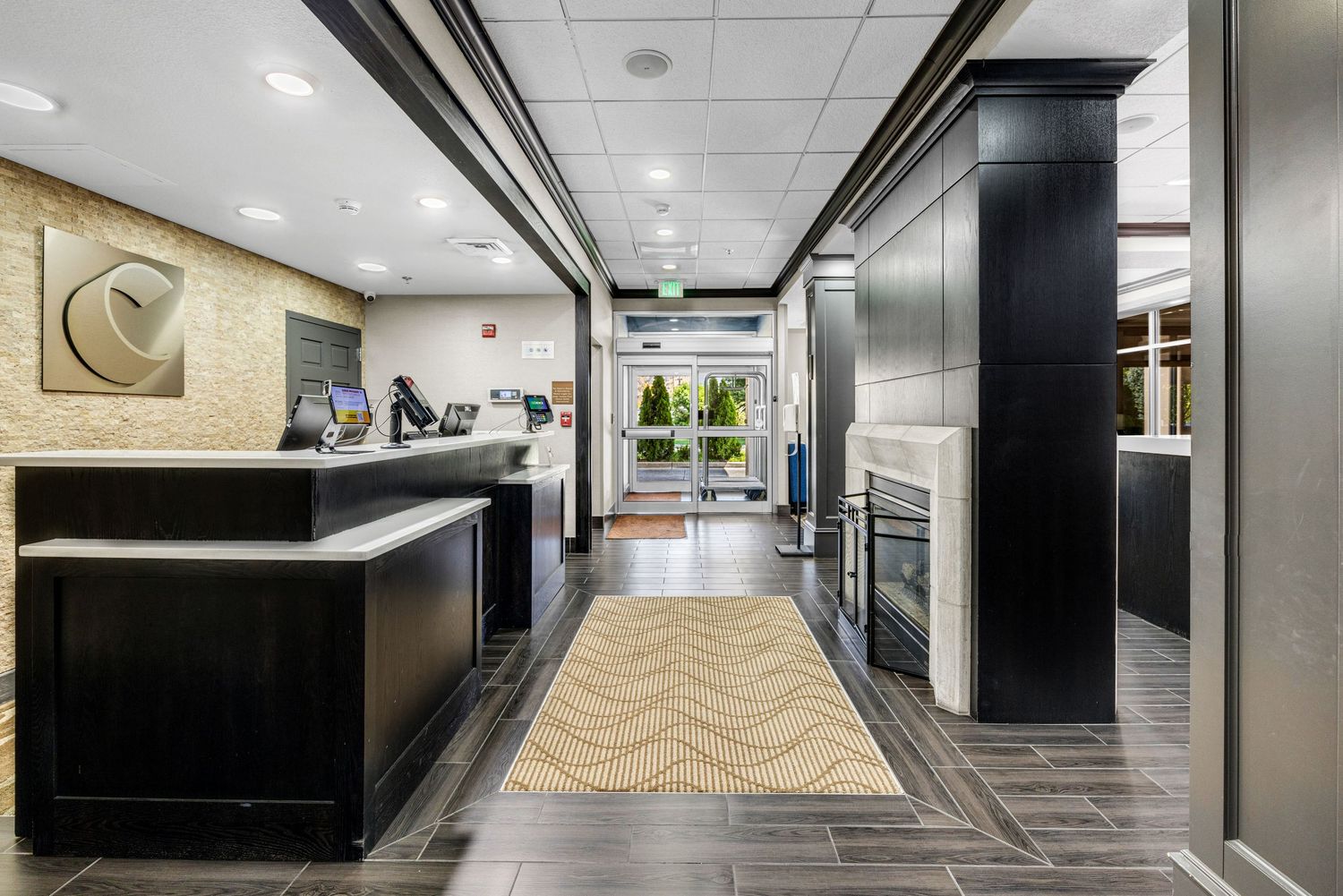 Modern office hallway with recessed lighting, black columns, and wood-textured wall panels.