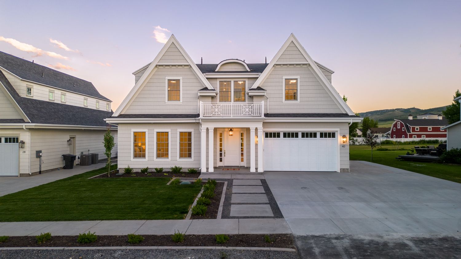 Modern farmhouse exterior with white siding and multiple gabled rooflines at dusk.