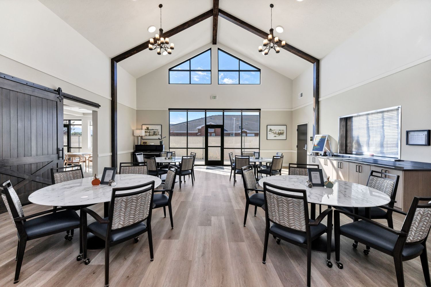 Contemporary dining area with vaulted ceiling, black chairs, and natural lighting.