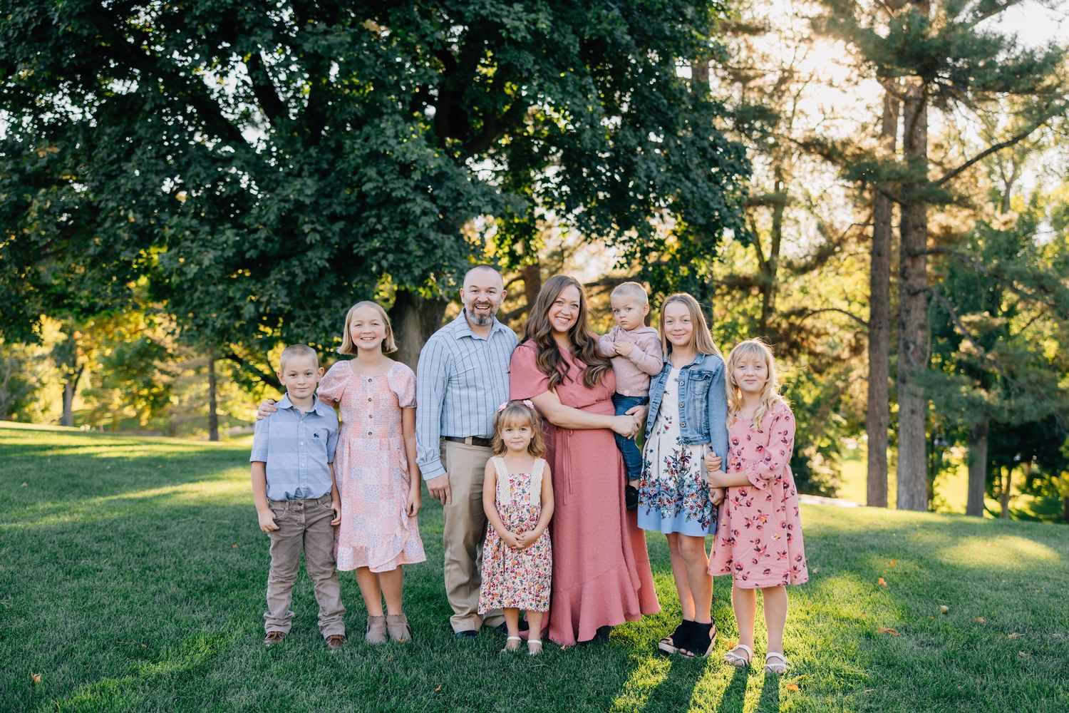 Family group photo session in a park during golden hour with coordinated pink outfits.