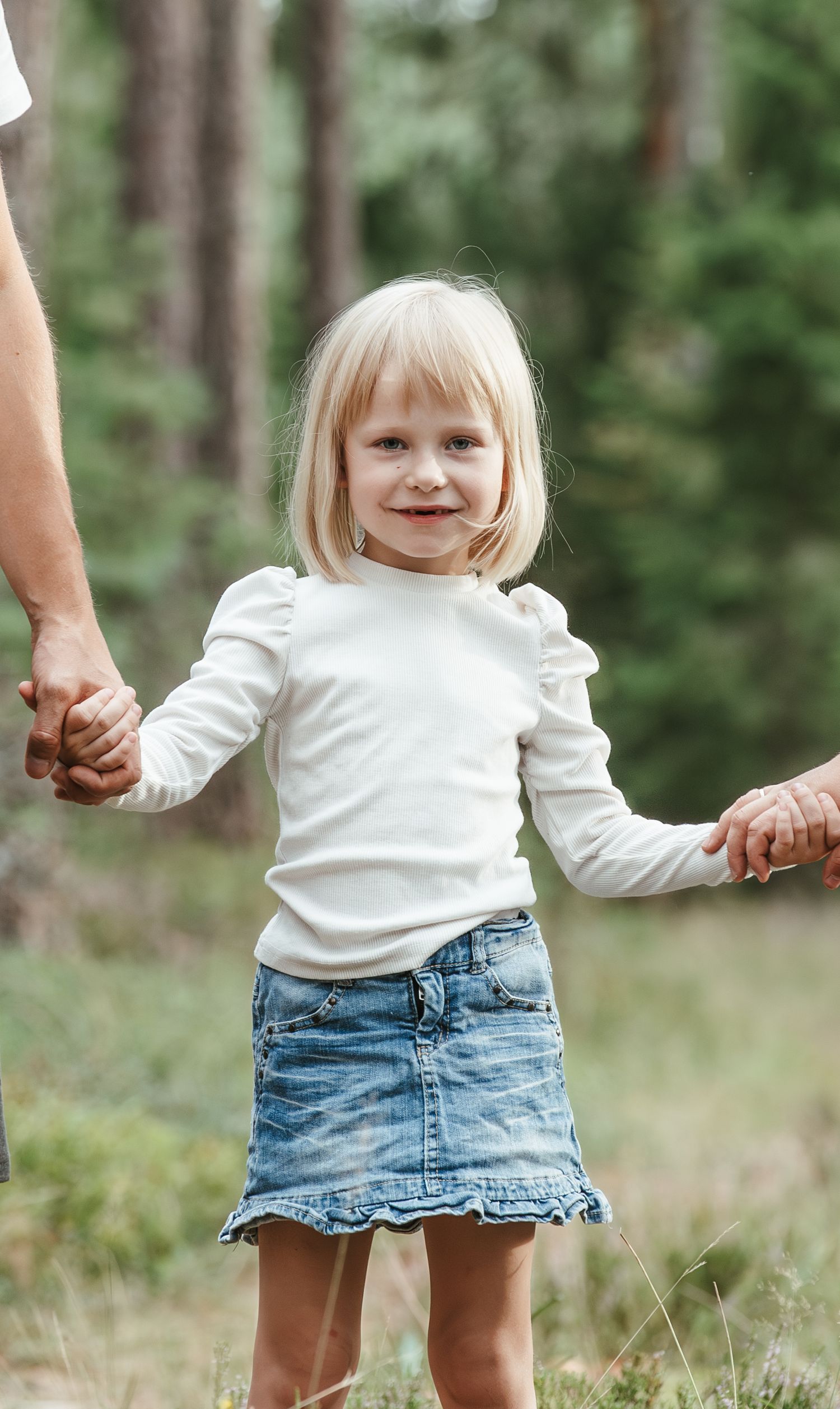 Maza meitenīte sadevusies rokās ar saviem vecākiem.