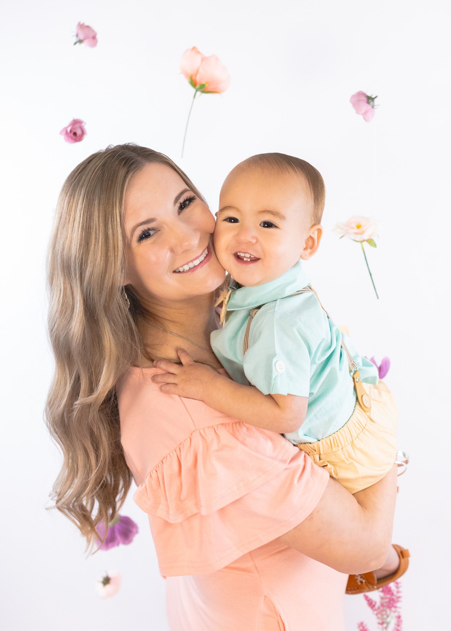 Joyful studio portrait showing affectionate moment with baby in mint shirt and yellow shorts.