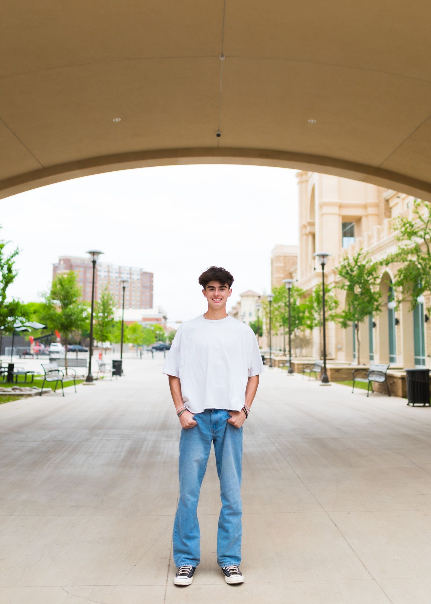 Student standing under architectural archway in casual attire.