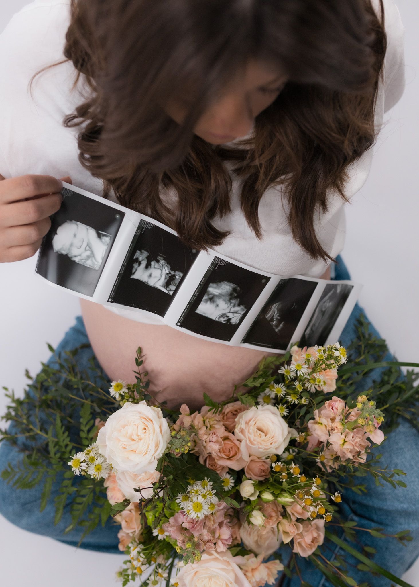 Pregnancy photo with ultrasound images and floral arrangement featuring pink roses.