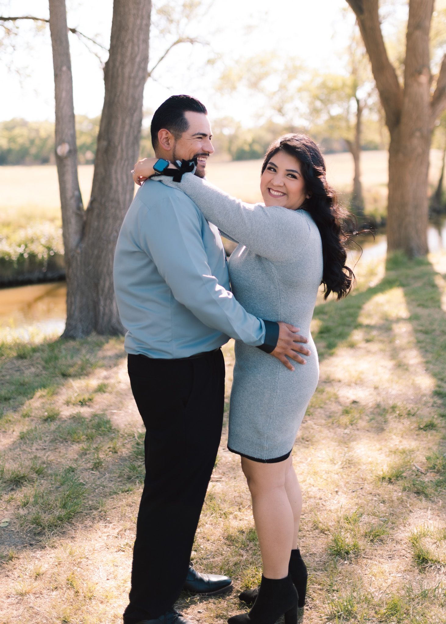 Couple in coordinating gray and black outfits embrace in a romantic outdoor portrait.
