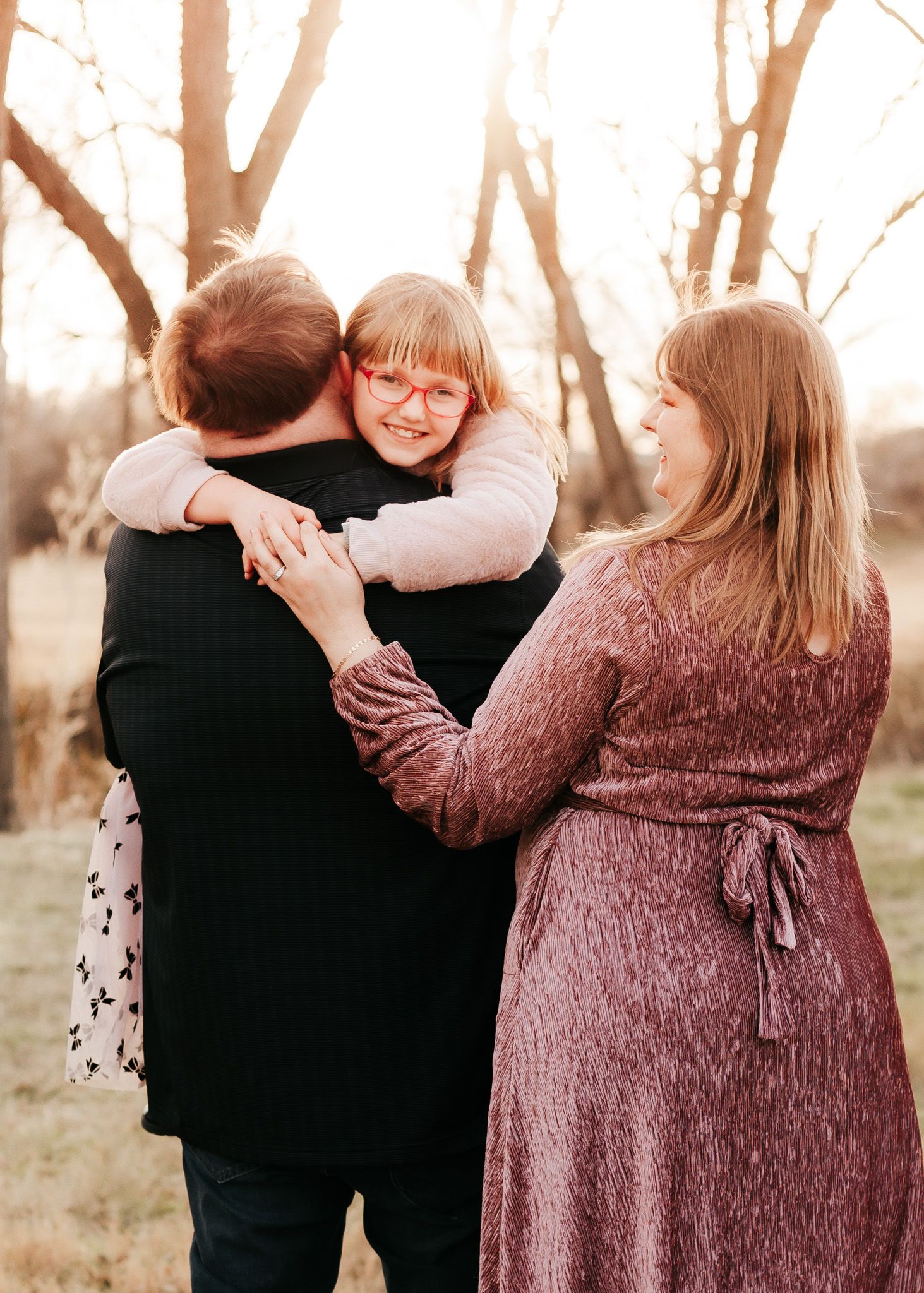 Joyful family moment captured in warm sunset light with hugs and laughter.