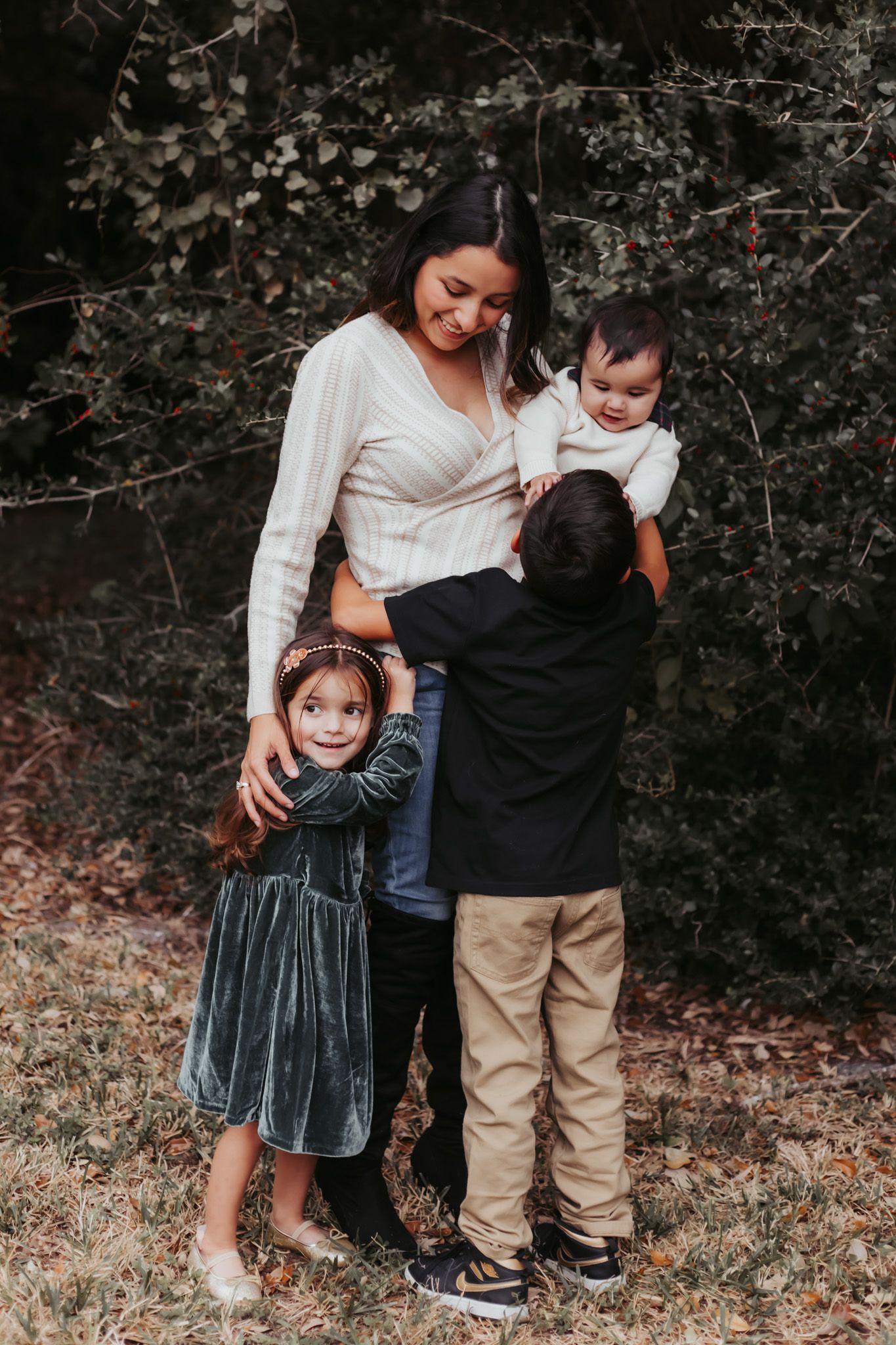 Mother and children sharing a sweet moment together against a backdrop of flowering branches.