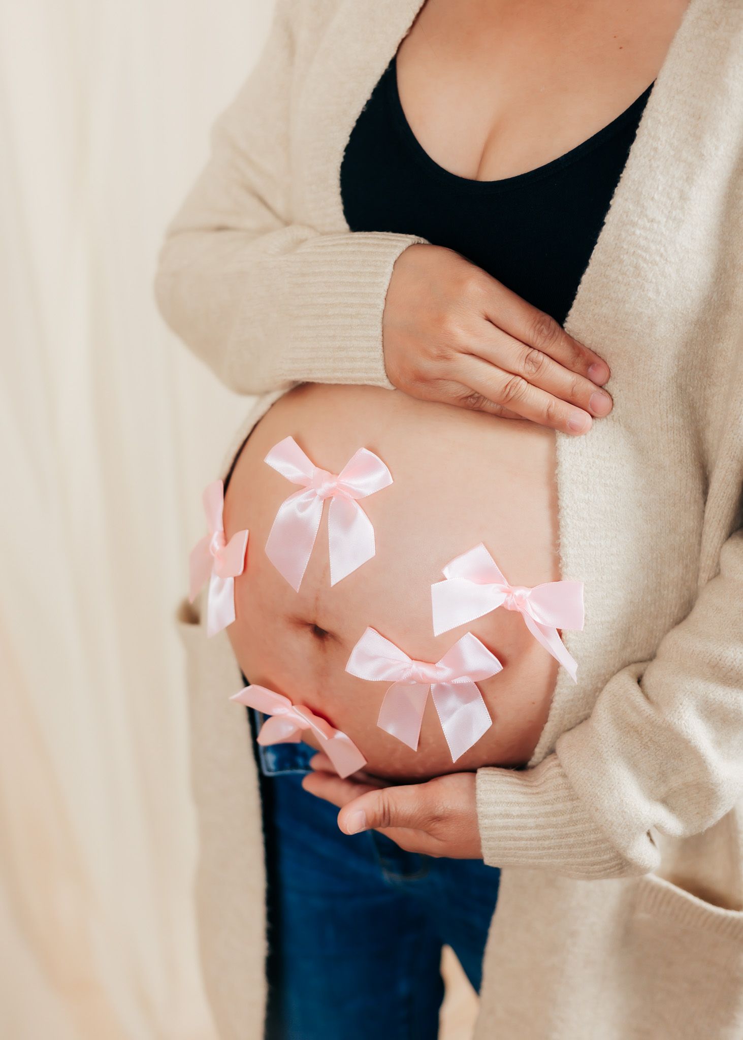 Maternity photos with pink bows decorating the pregnant belly.