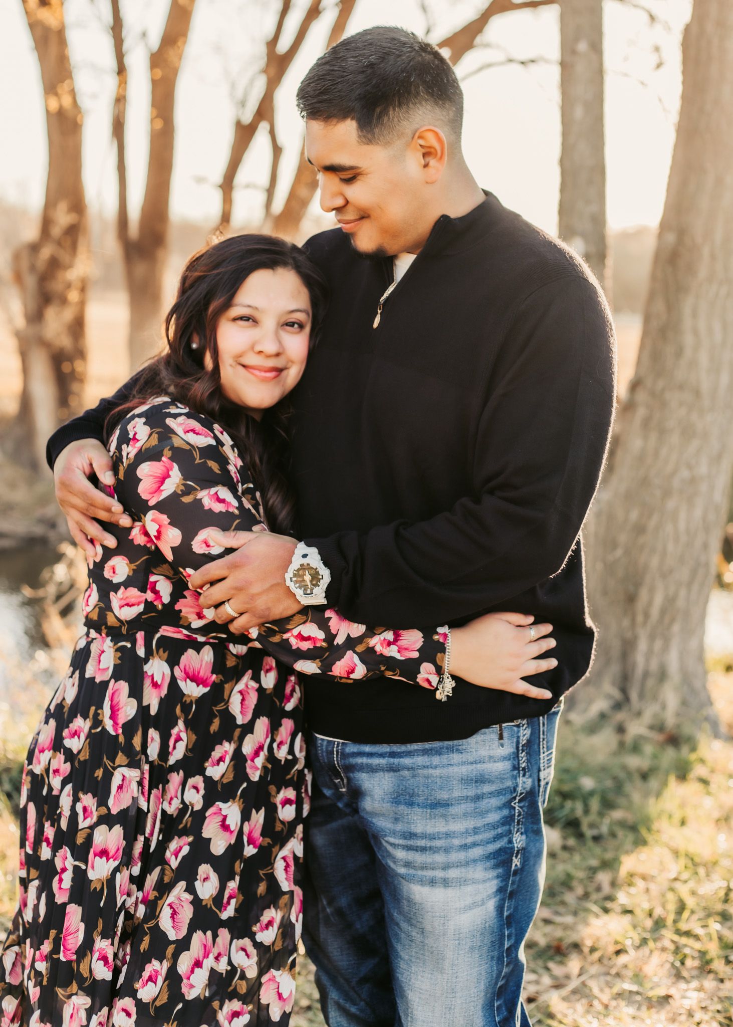 Couple in casual attire embracing and smiling during an outdoor photoshoot.