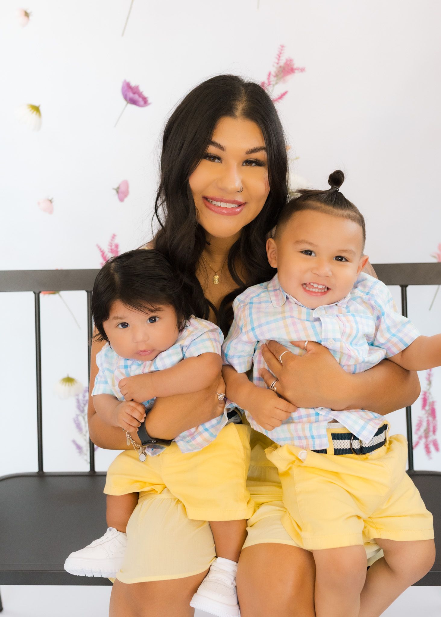 Two babies in matching blue and yellow outfits share a sweet moment during a photo session.