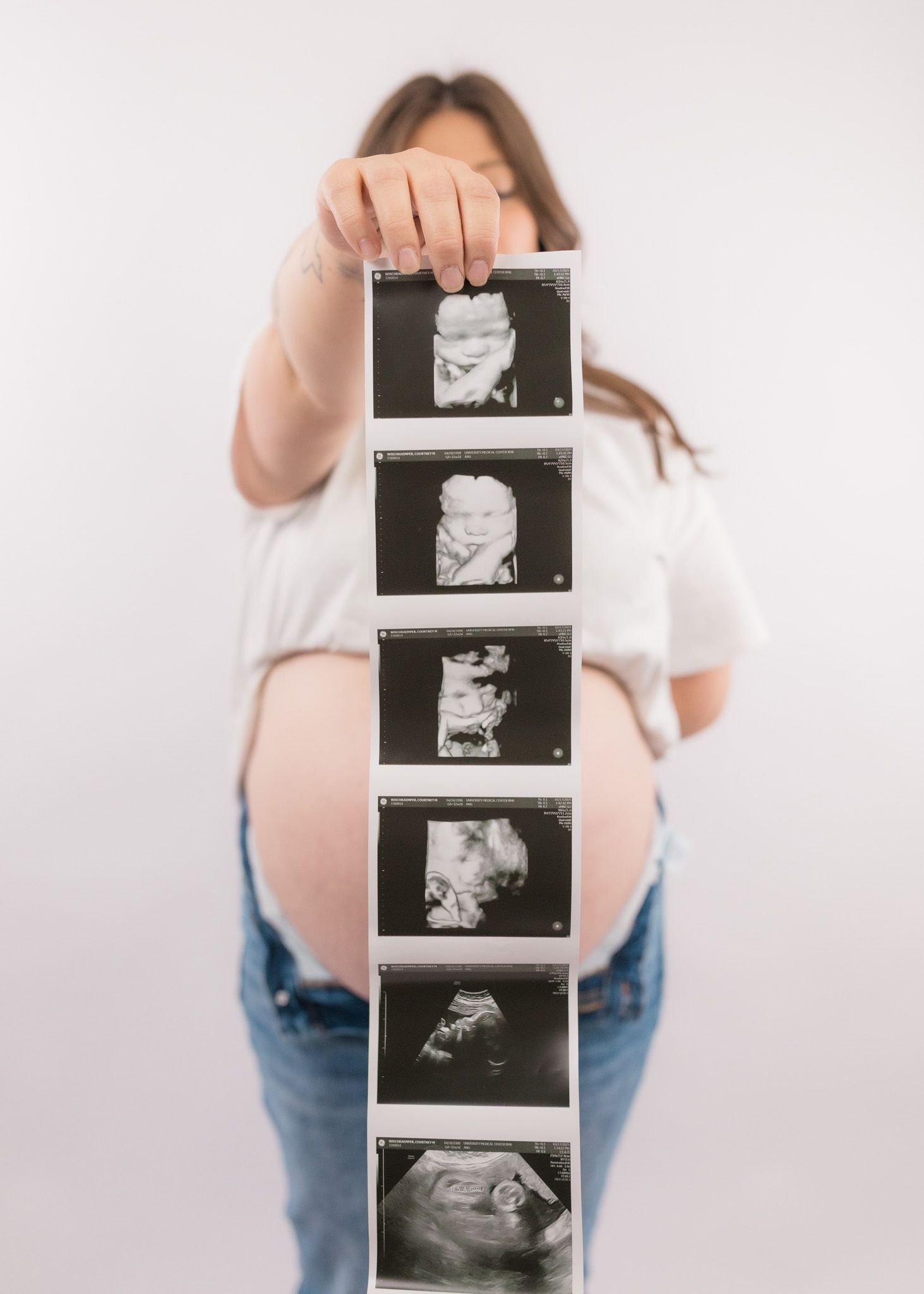 Expecting mother holding strip of ultrasound photos showing baby's development stages.