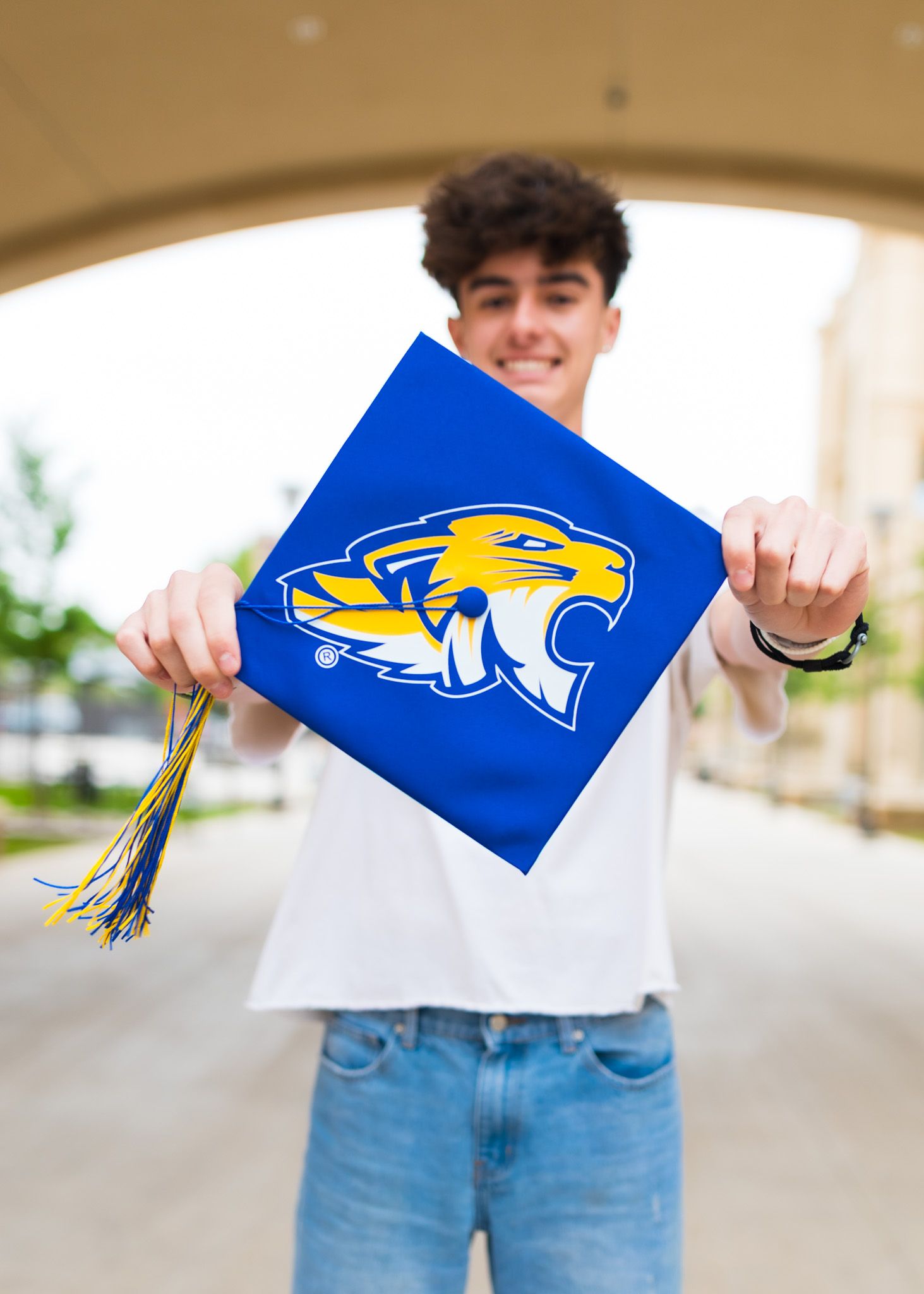 Blue graduation cap decorated with university mascot logo and gold tassel.