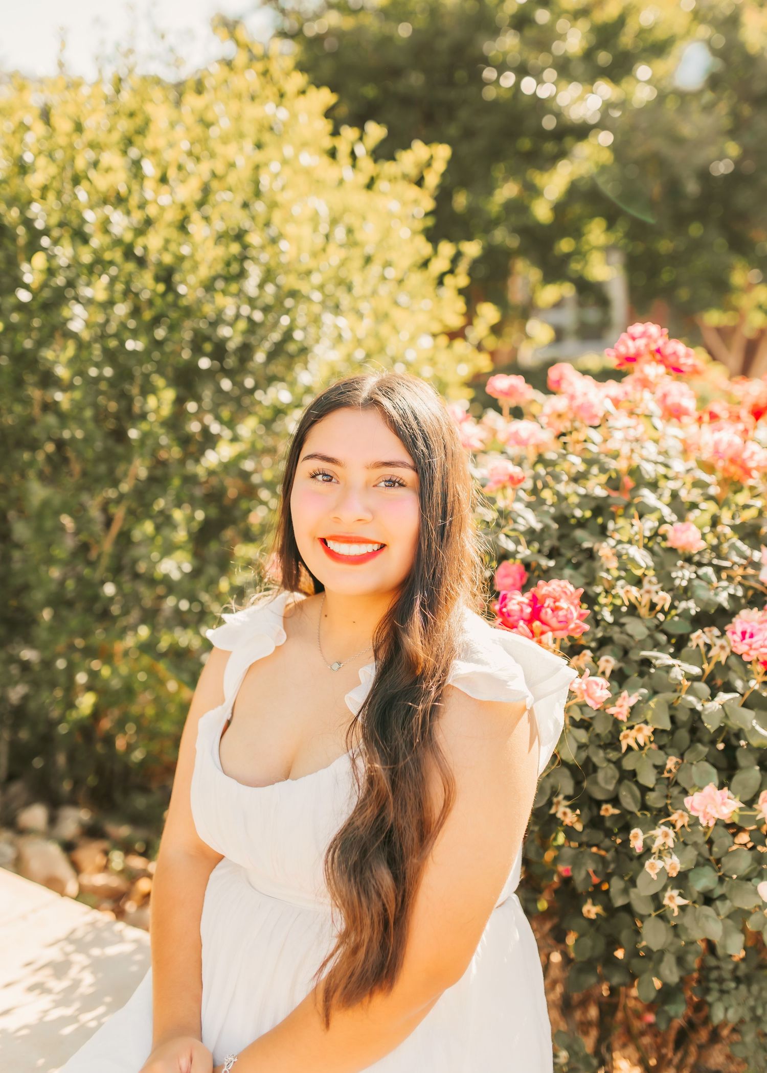 Garden photoshoot with blooming roses and golden sunlight in the background.