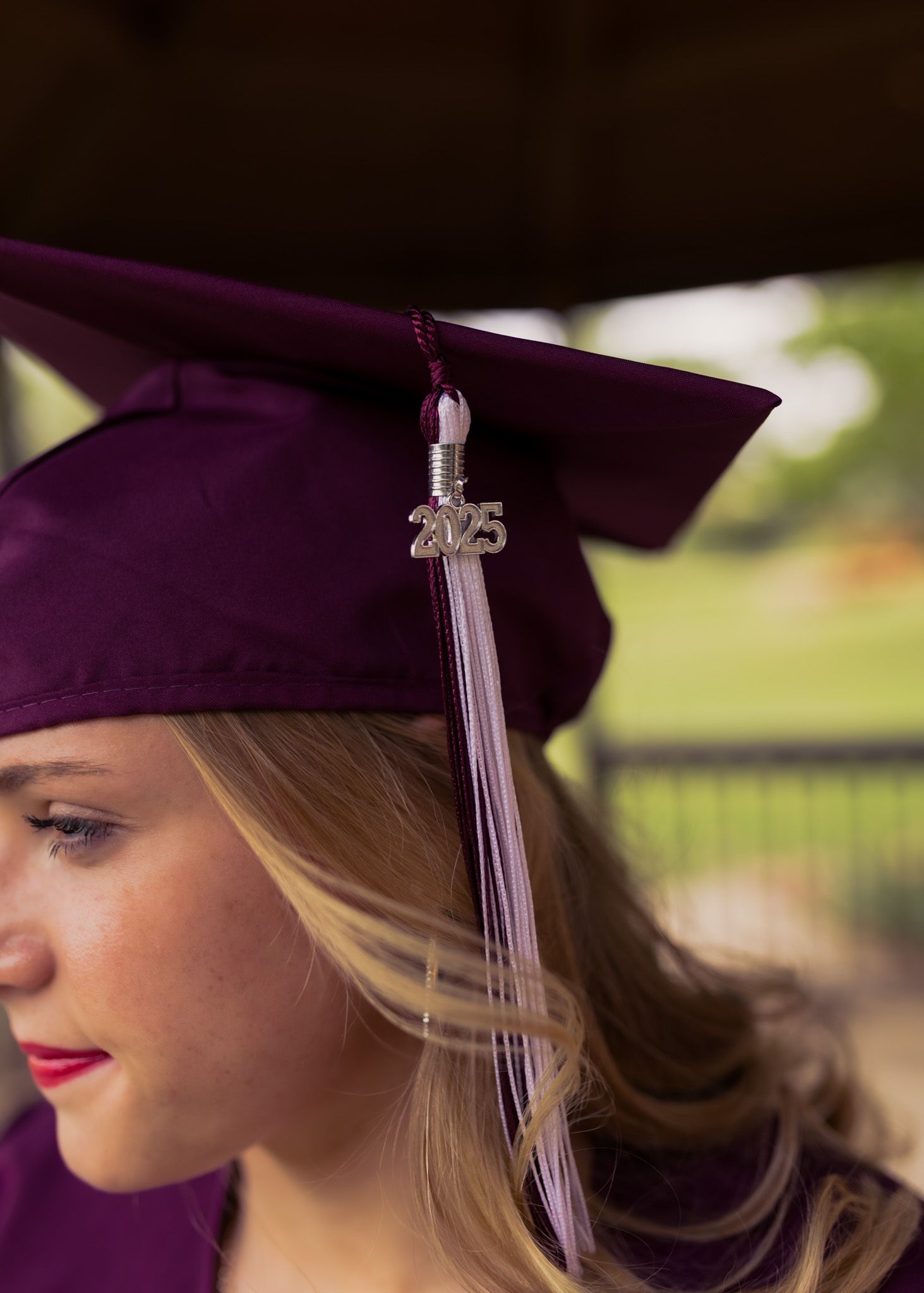 Close-up of purple graduation cap with tassel on graduate in outdoor setting.