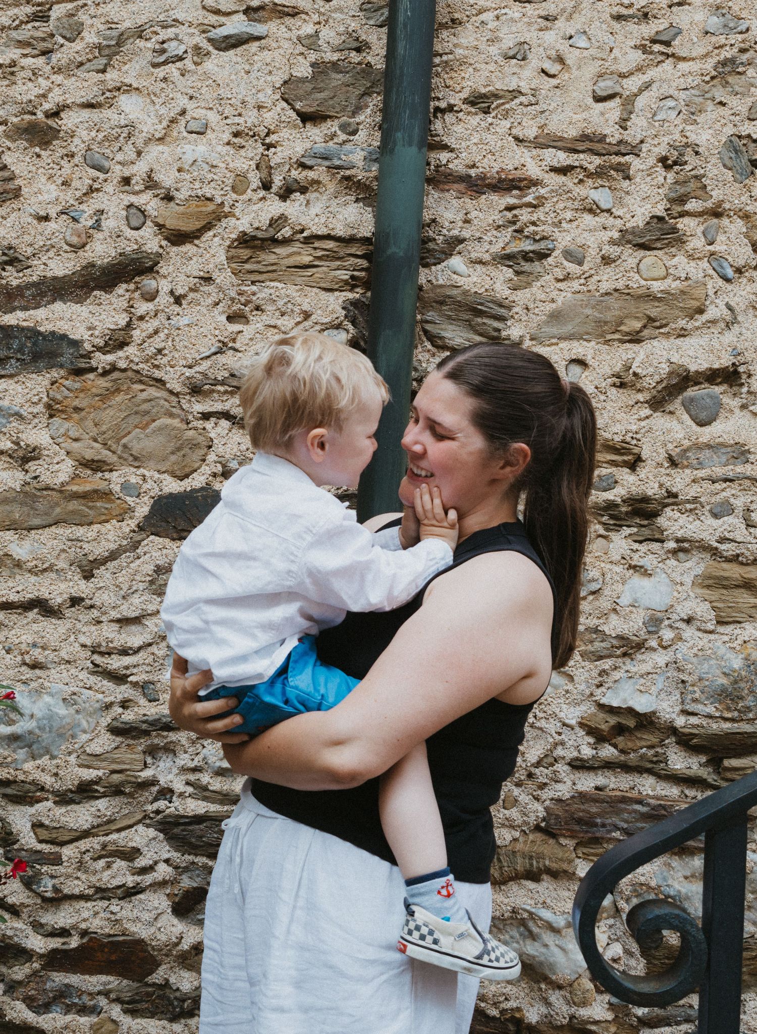 A tender moment between parent and child against a rustic stone wall background.