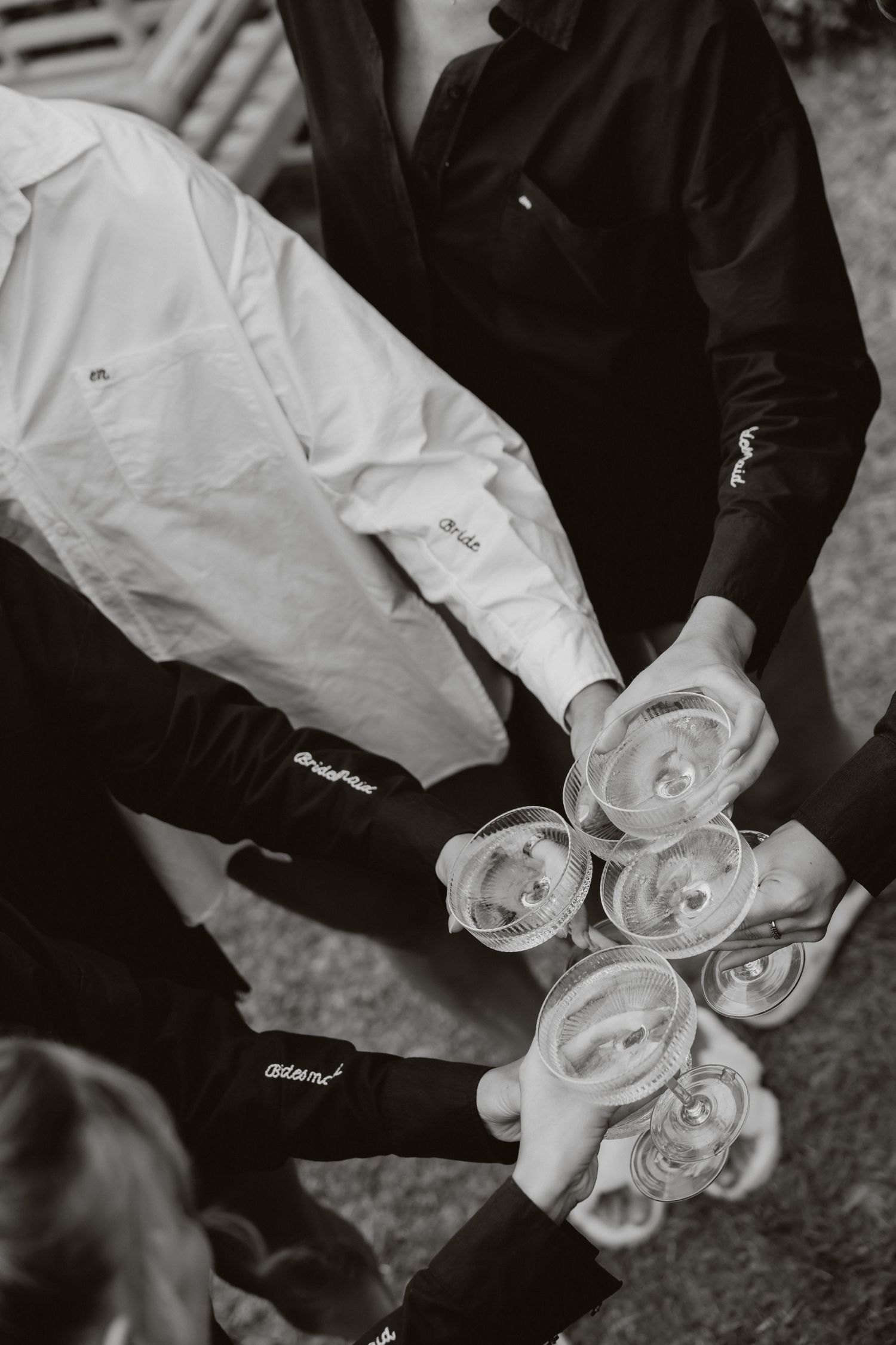Black and white overhead photo of wedding party clinking champagne glasses in a celebratory toast at The Woodhouse, Wollombi..